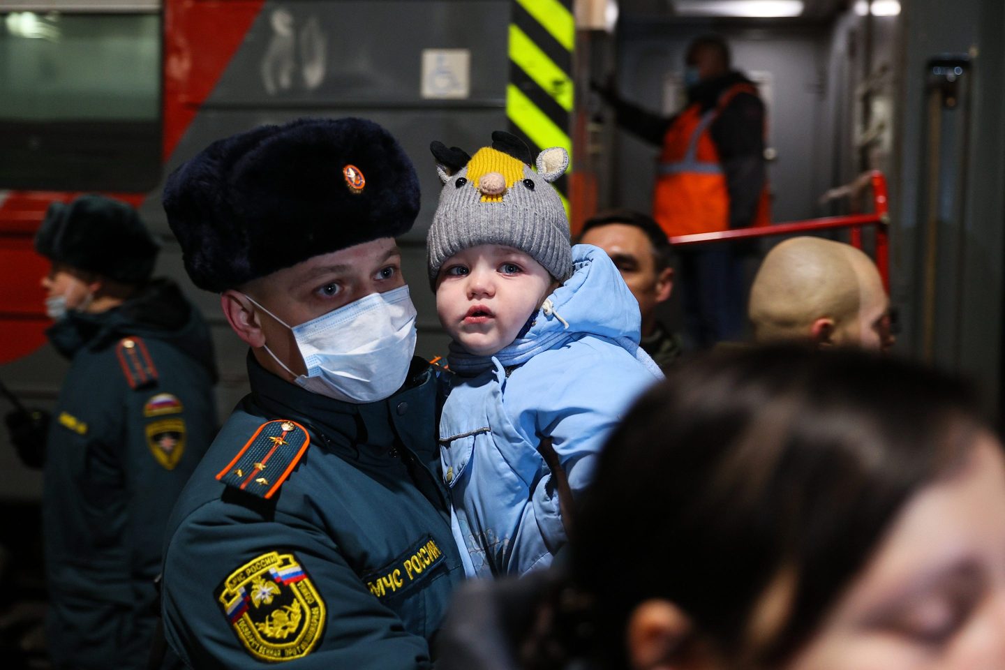 A Russian Emergencies Ministry officer carries a child as people evacuated from Donbass arrive at a railway station.