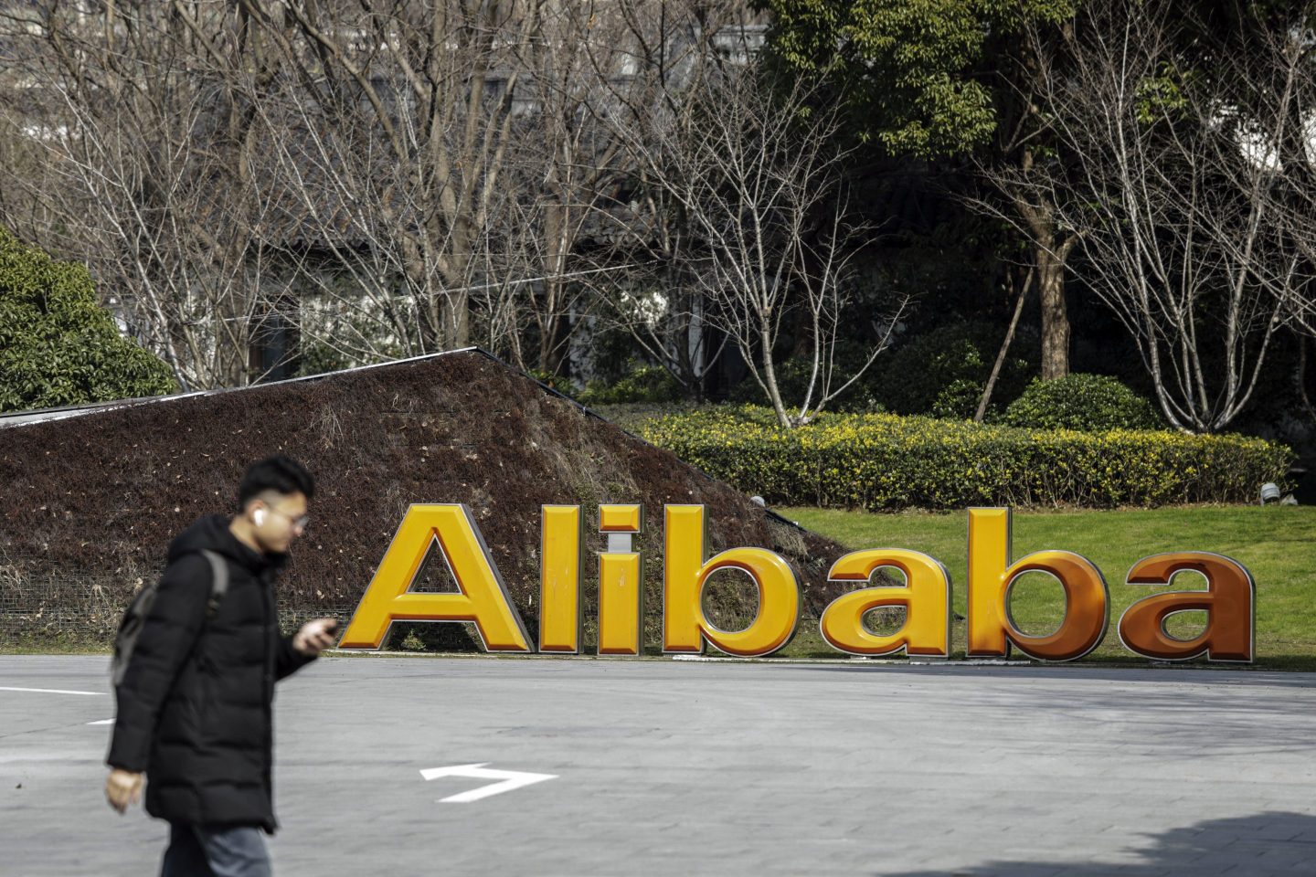 A man walks in front of a sign displaying Alibaba