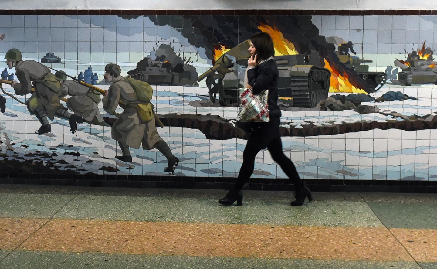A woman walks past a WWII mural in Ukraine.