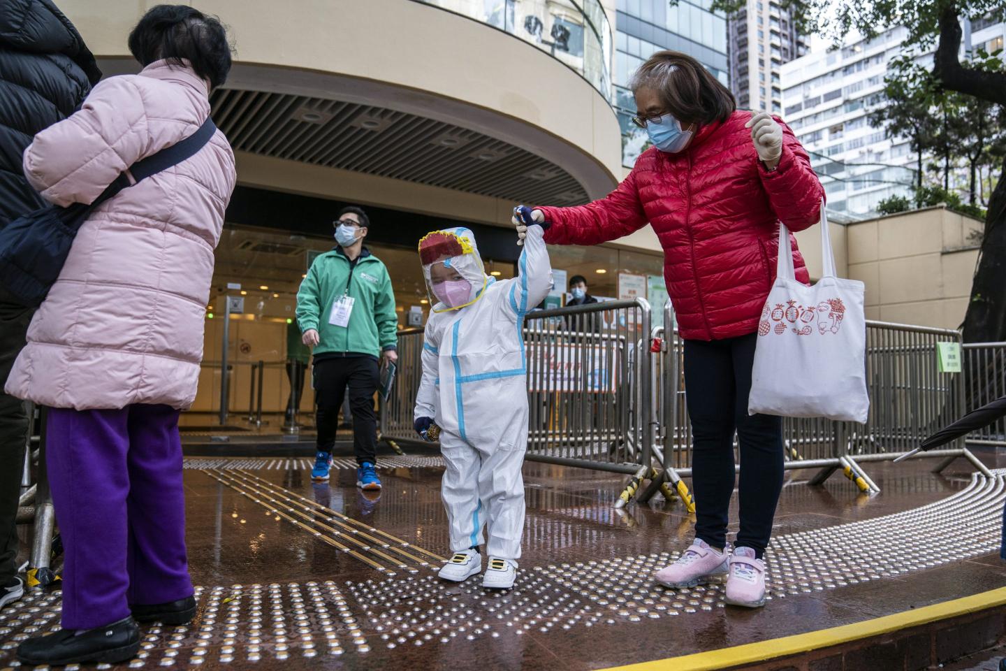 A toddler in a hazmat suit lines up in a vaccine queue.