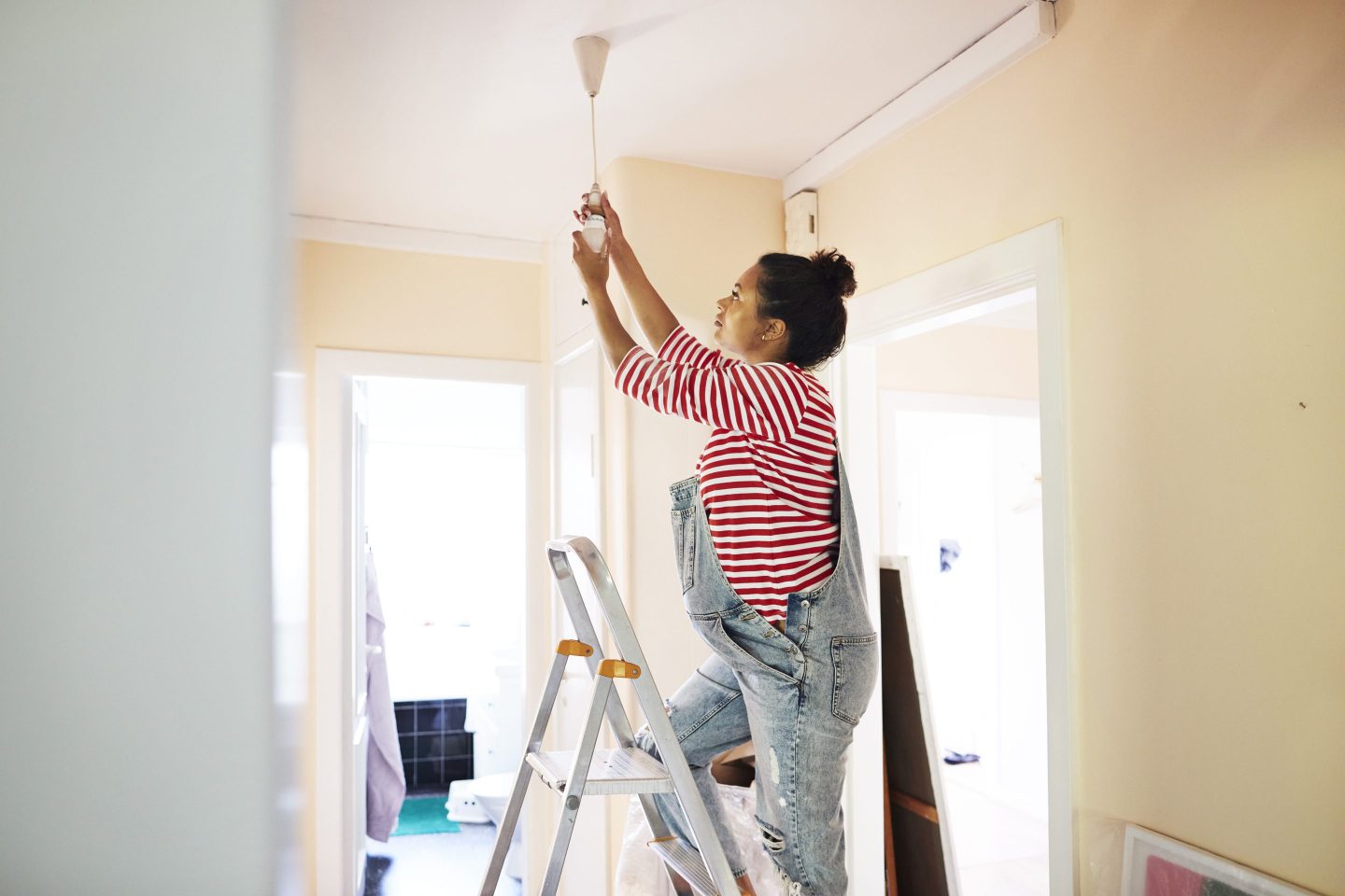 Pregnant young woman standing on a ladder