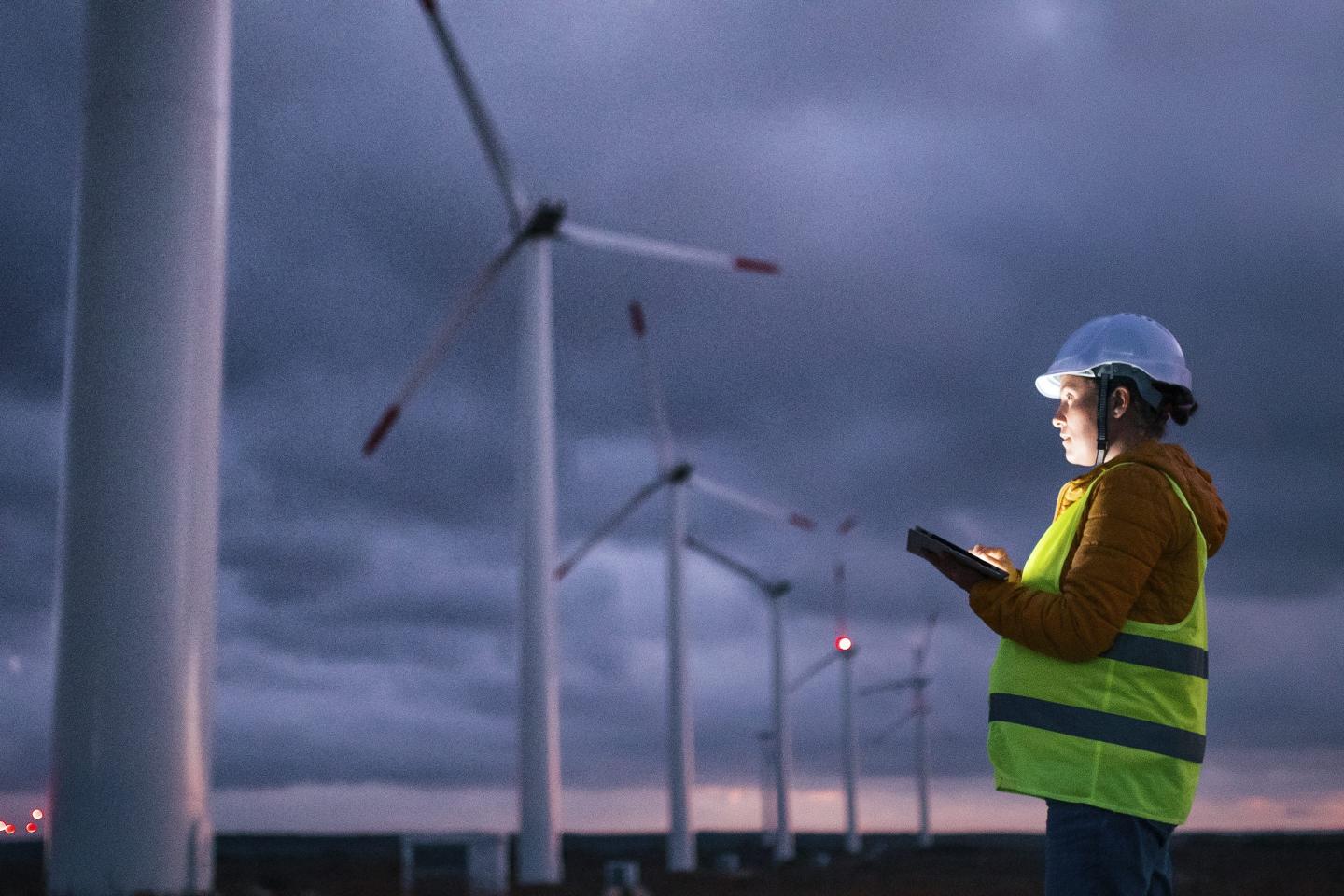 An engineer performs maintenance at a wind-turbine farm.
