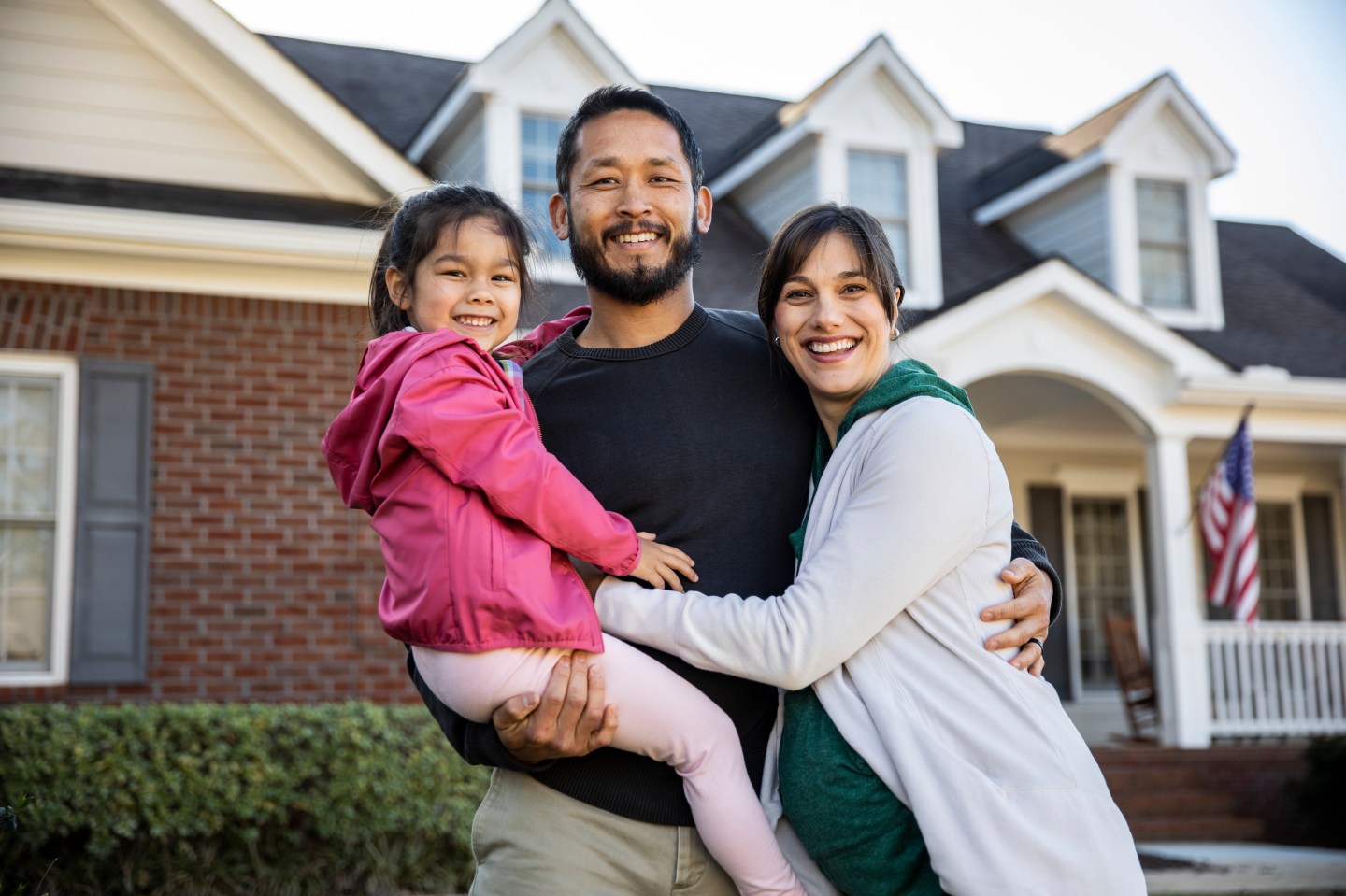 A family standing in front of a suburban home.