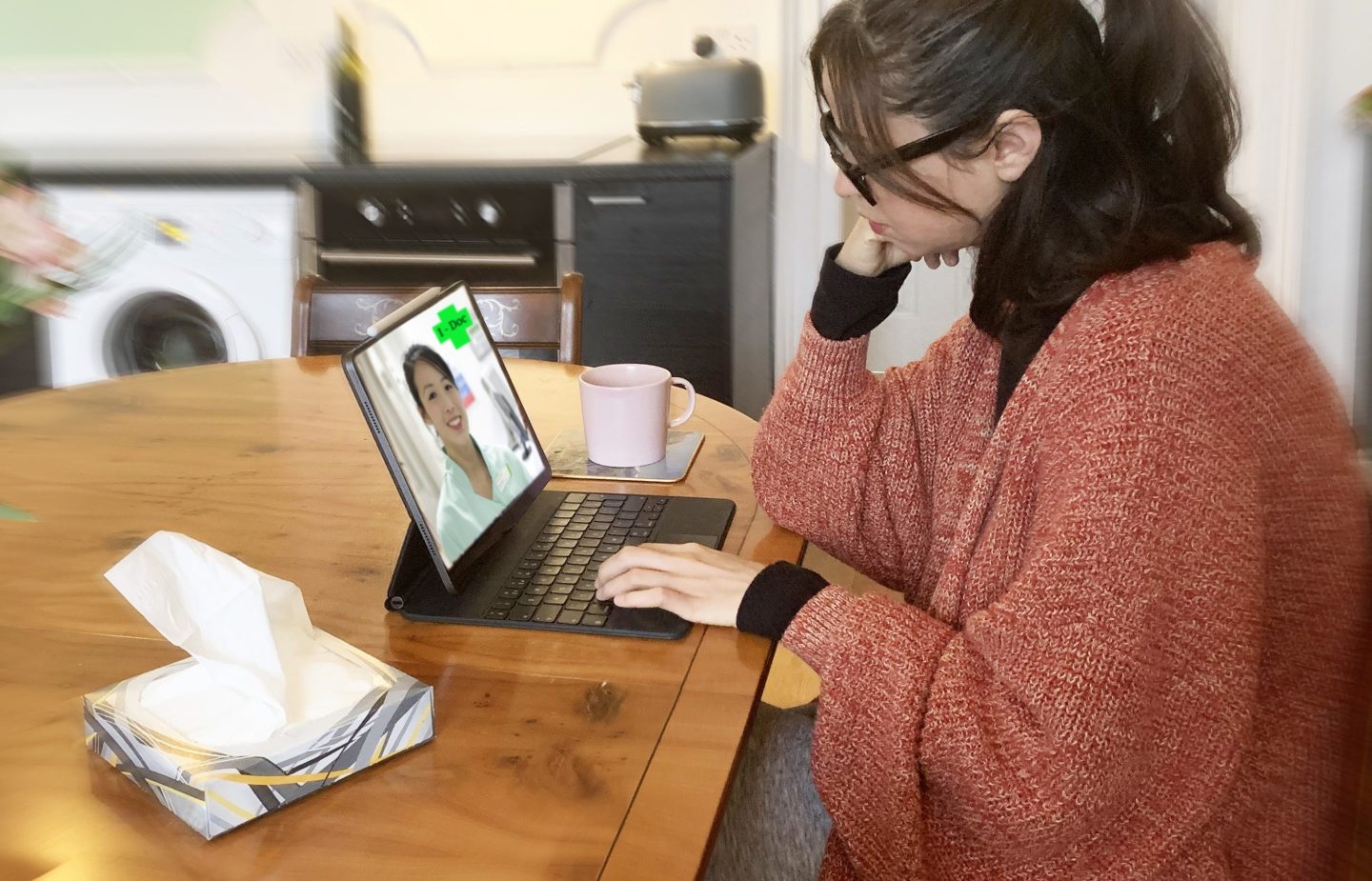 Woman with a box of tissues next to computer doing a telemedicine appointment
