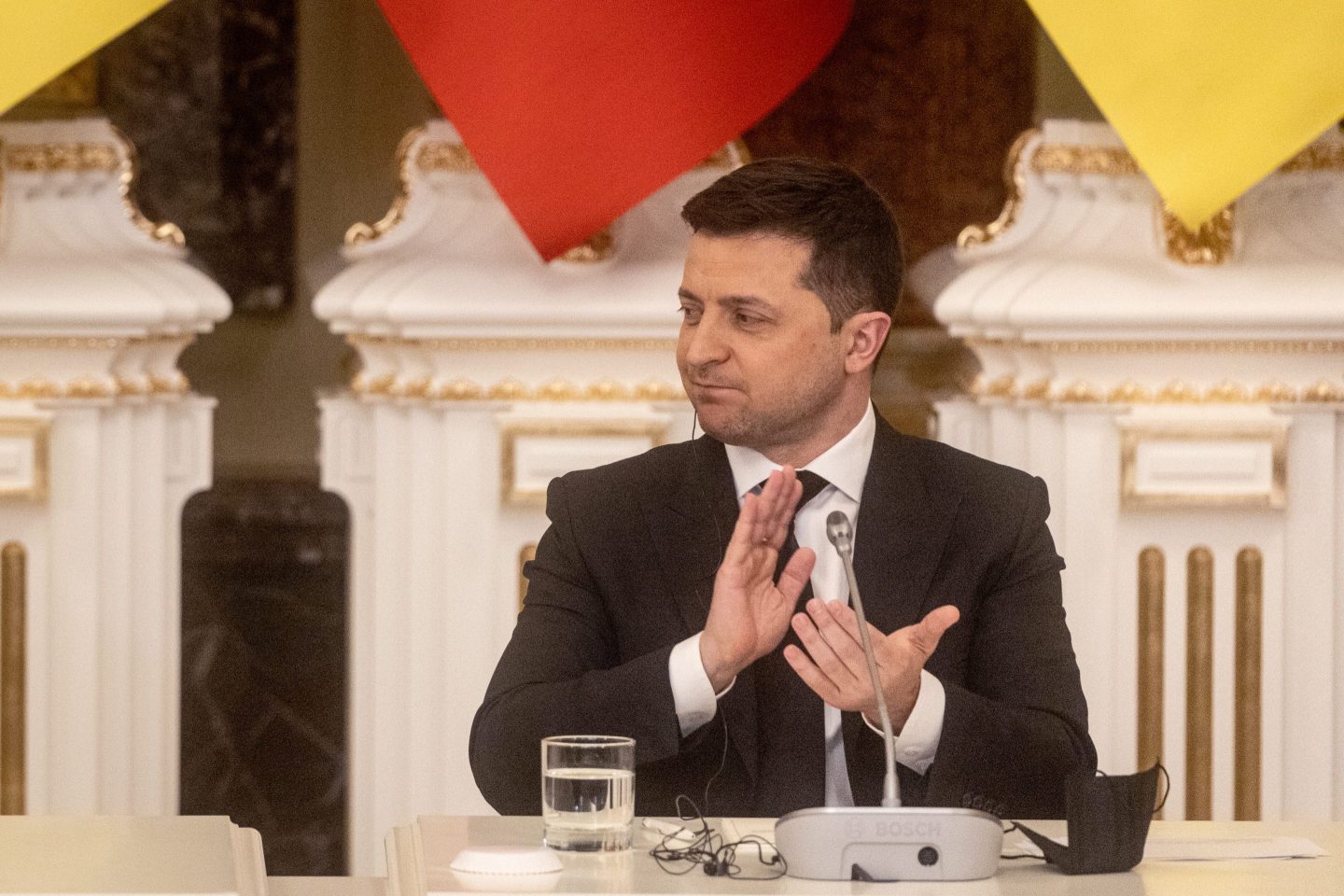 Ukraine President Volodymyr Zelenskyy sits at a table, clapping, in February 2022