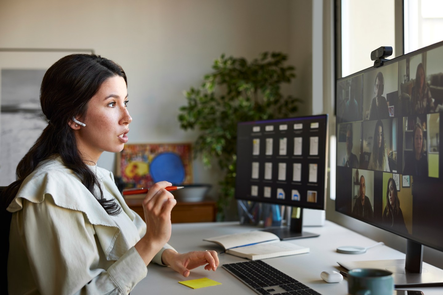 Businesswoman gesturing during video conference with colleagues. Female professional is using computer at desk. She is in home office.