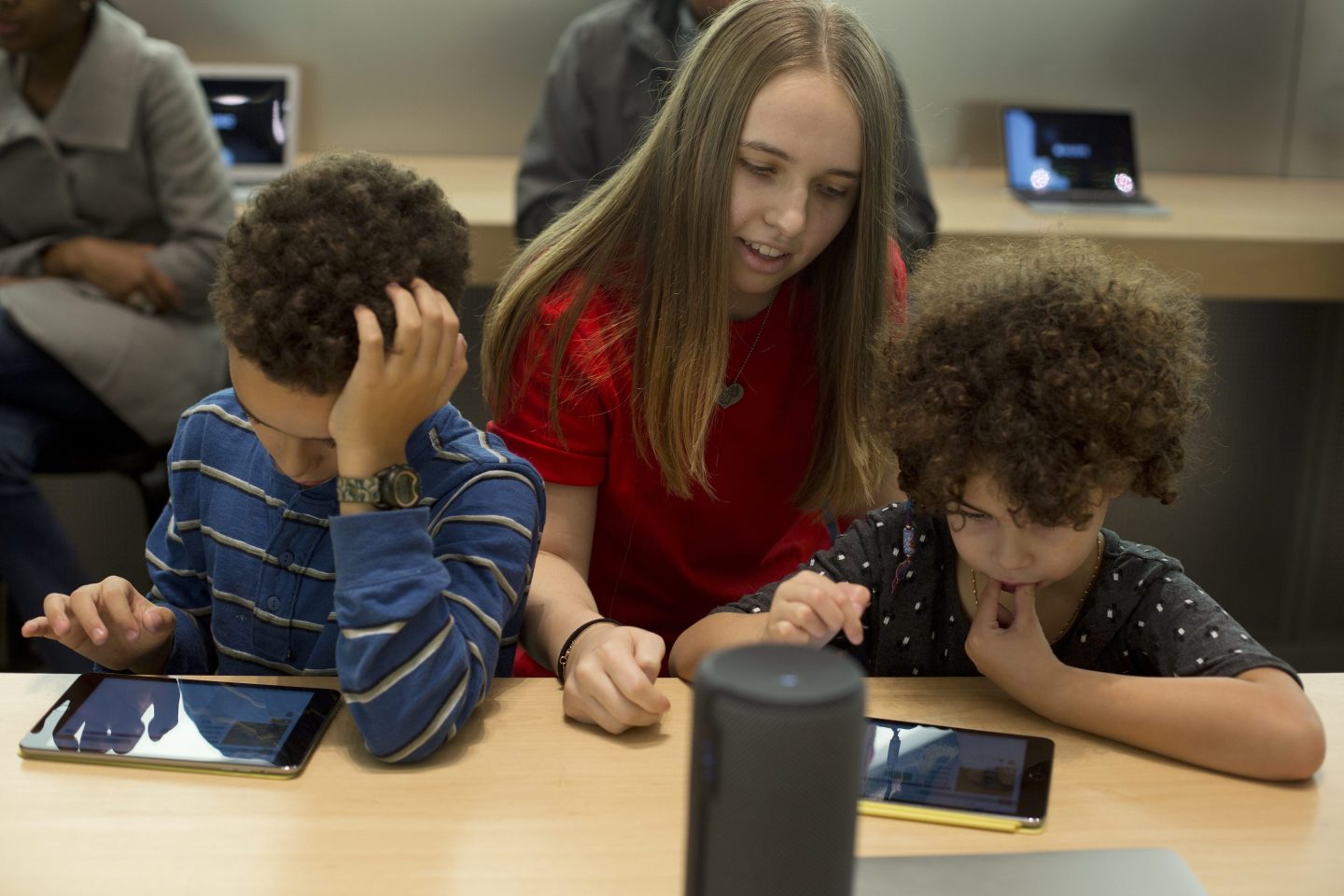 An employee assists kids with building a video game using code on an Apple Inc. iPad Mini during the Hour of Code workshop at an Apple store in New York