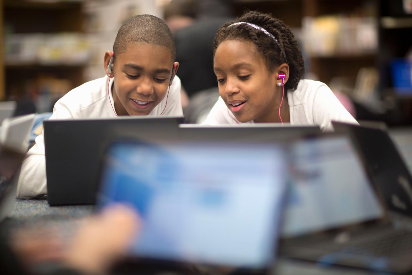 Two students work on their laptops