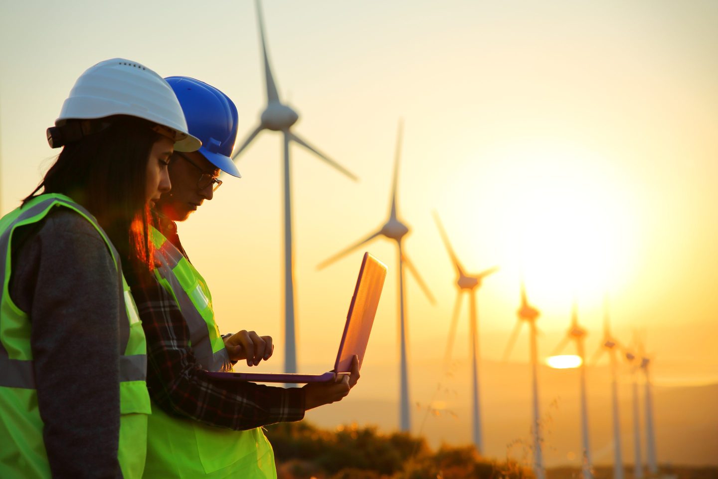 Workers standing near a row of wind energy turbines