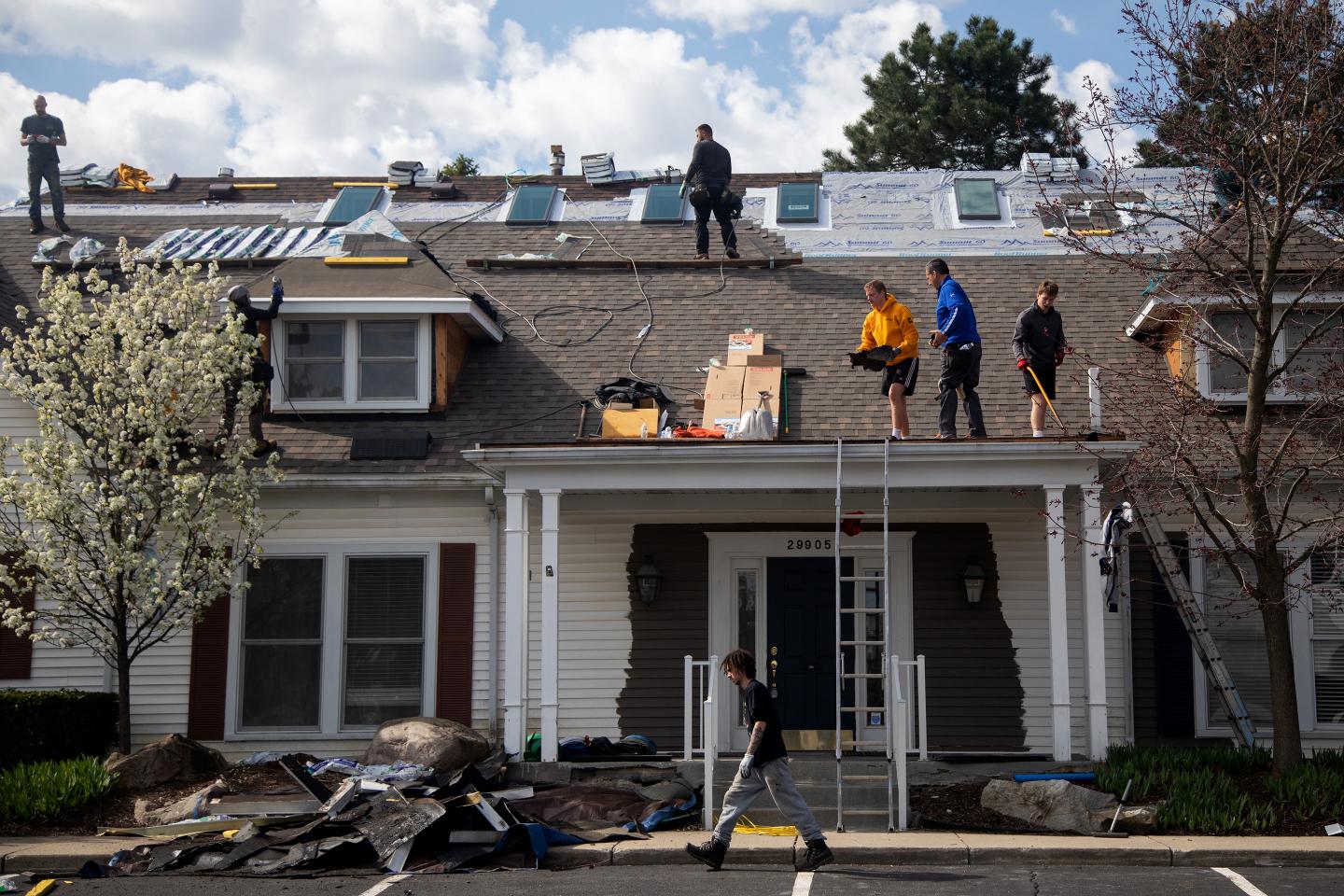 Construction workers lay shingles on the roof of a house in Farmington Hills, Michigan, U.S., on Thursday, May 7, 2020.