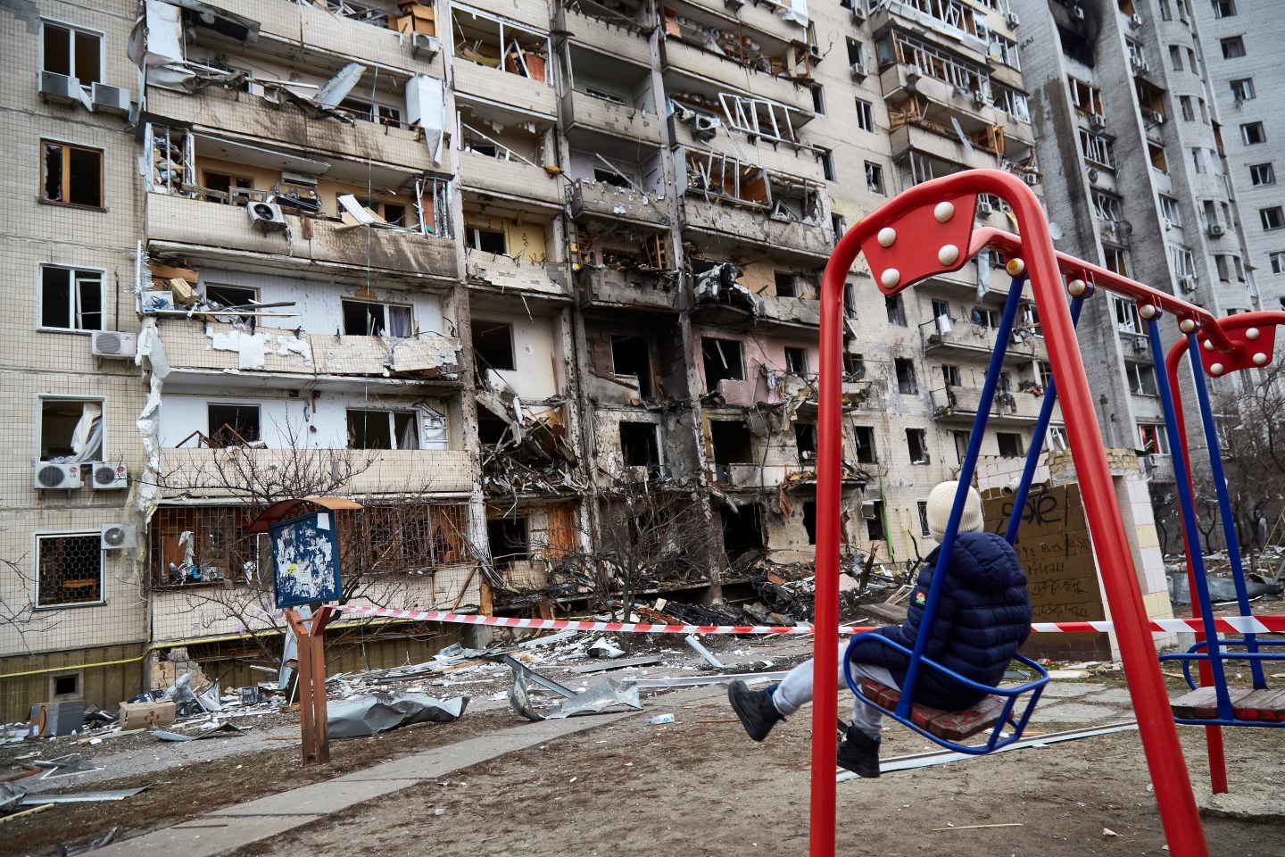A child plays on a swing outside a residential building damaged by a missile on in Kyiv, Ukraine.