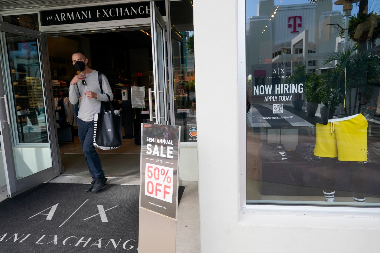 For sale and hiring signs are displayed at an Armani Exchange store, Friday, Jan. 21, 2022, in Miami Beach, Fla.