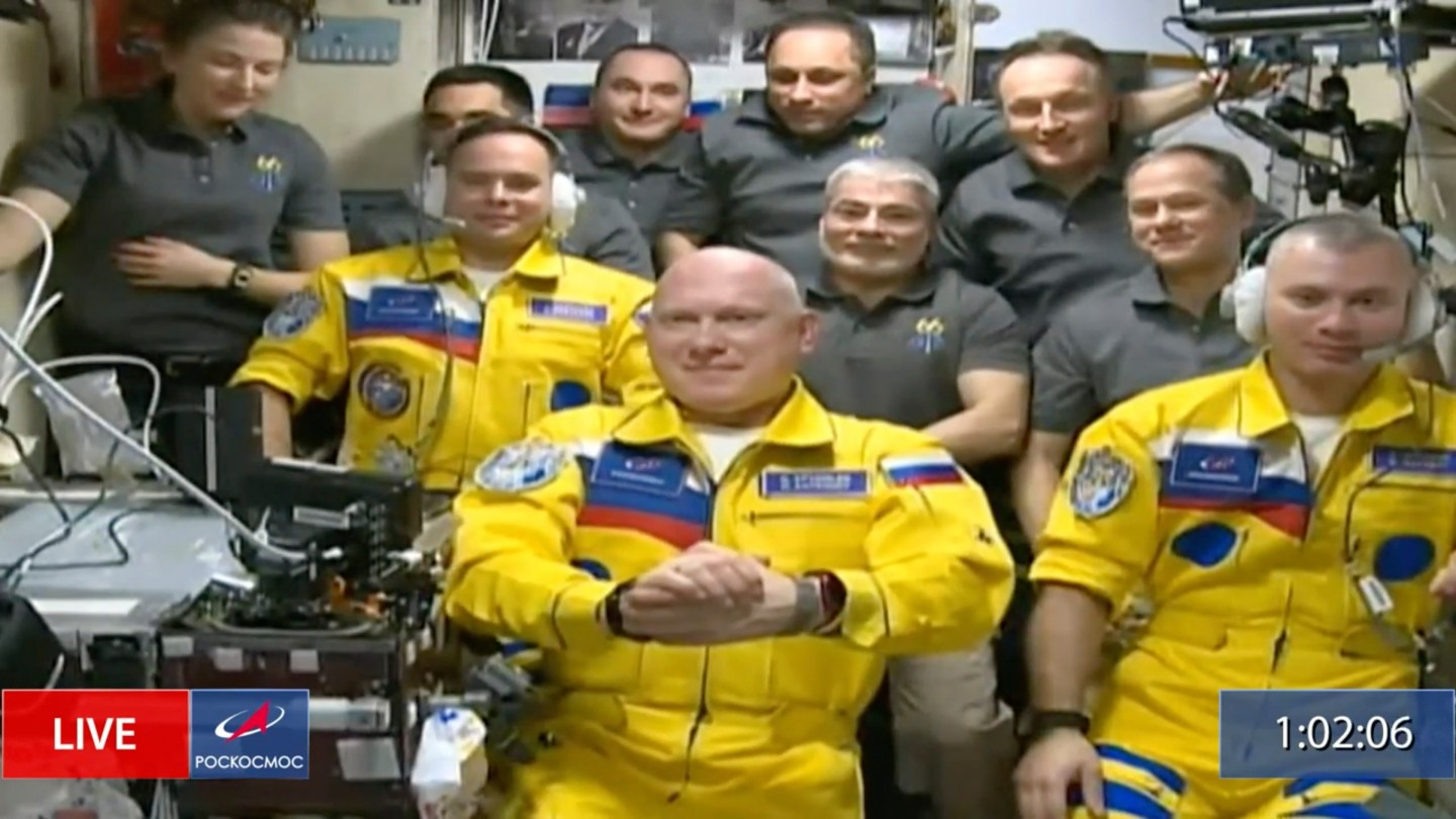 In this frame grab from video provided by Roscosmos, Russian cosmonauts Sergey Korsakov, Oleg Artemyev, and Denis Matveyev are seen during a welcome ceremony after arriving at the International Space Station, Friday, March 18, 2022, the first new faces in space since the start of Russia’s war in Ukraine. The crew emerged from the Soyuz capsule wearing yellow flight suits with blue stripes, the colors of the Ukrainian flag.