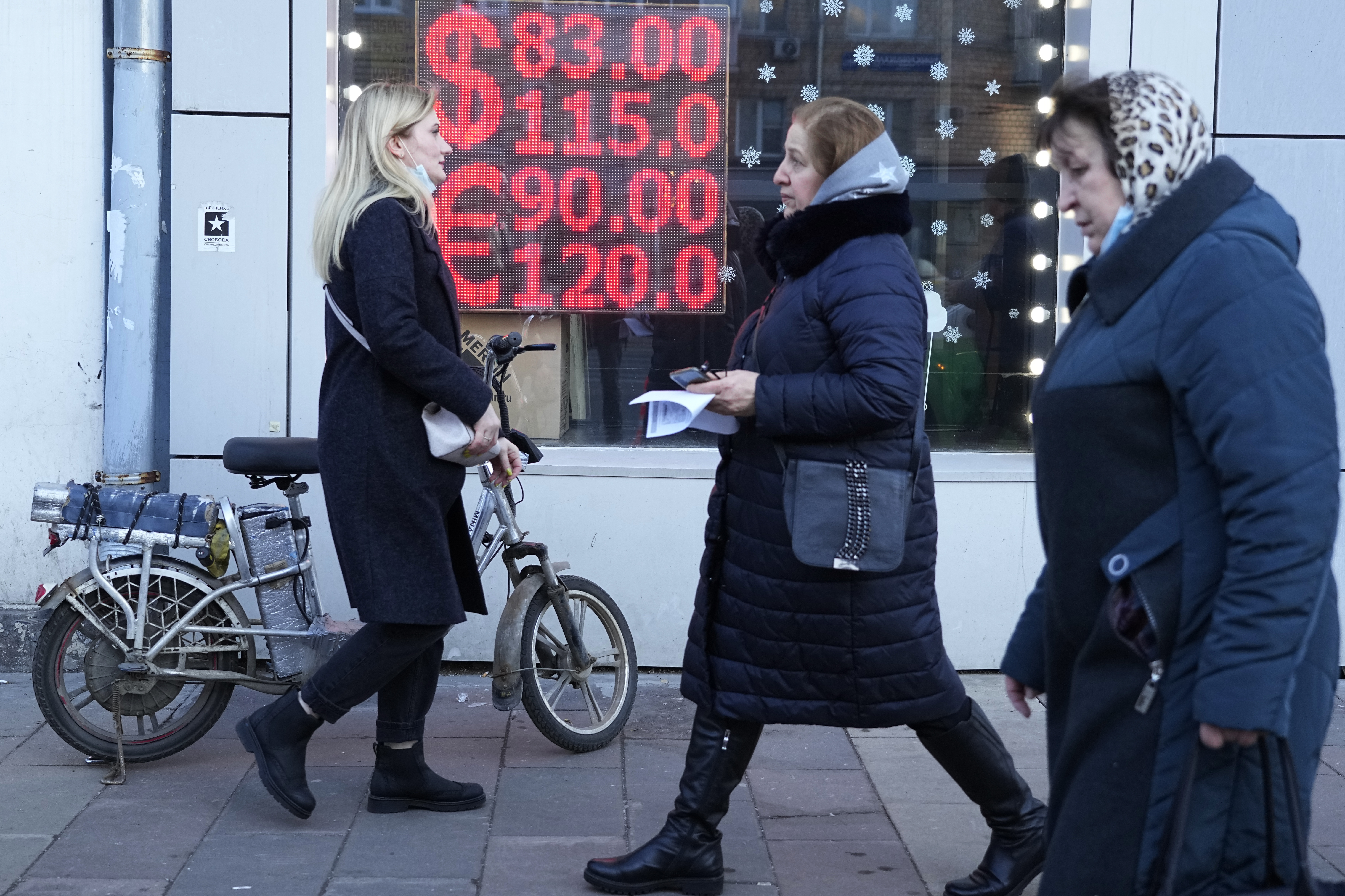 People walk past a currency exchange office screen displaying the exchange rates of U.S. Dollar and Euro to Russian Rubles in Moscow, on Feb. 28, 2022. 