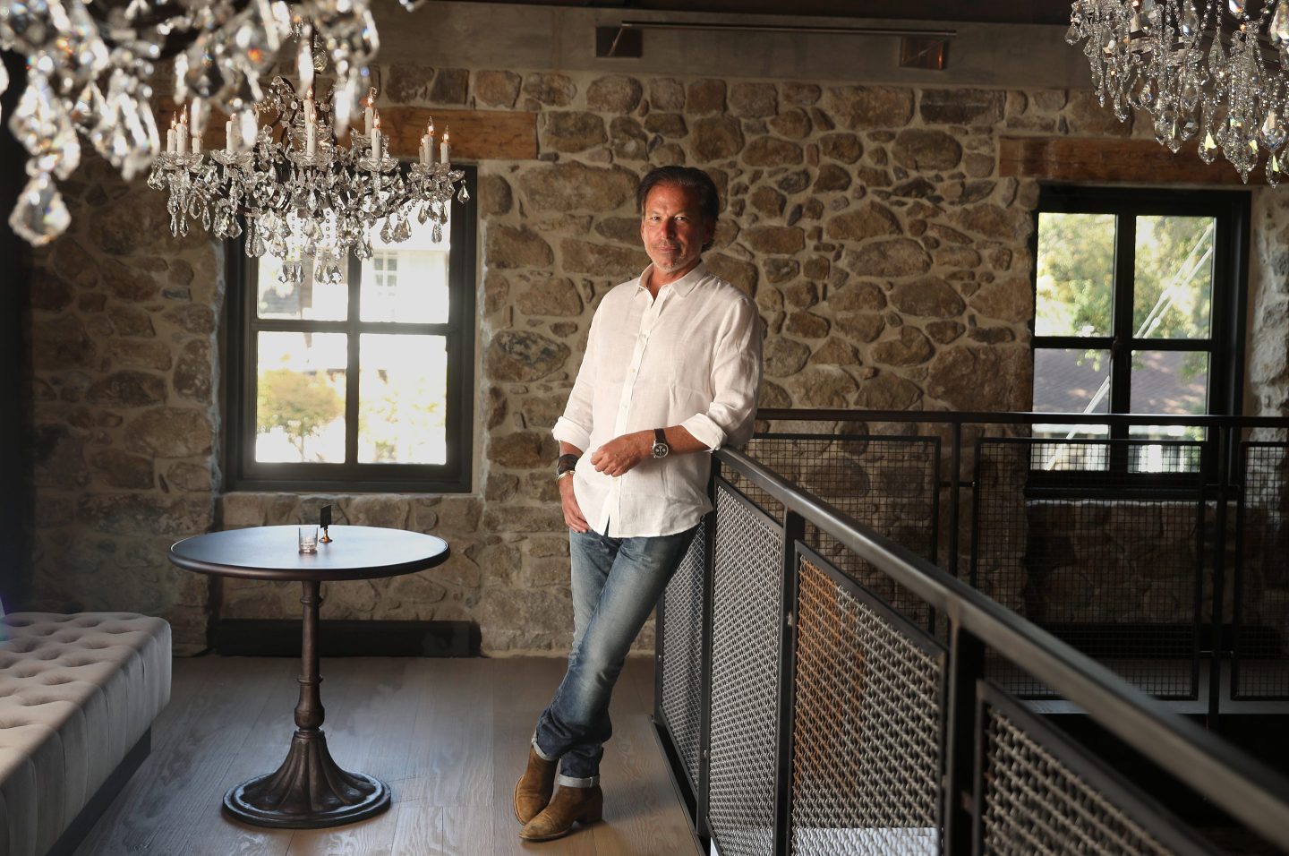 RH CEO Gary Friedman leans on a railing while posing for a photo in RH Yountville's two-story wine vault.