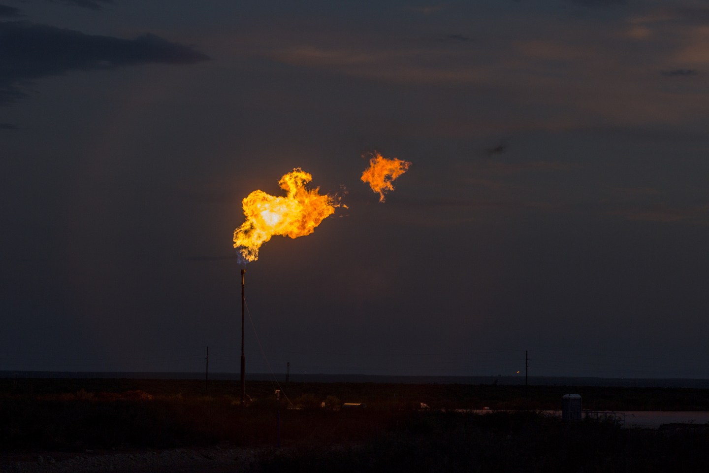 A gas flare burns in an oil field at night