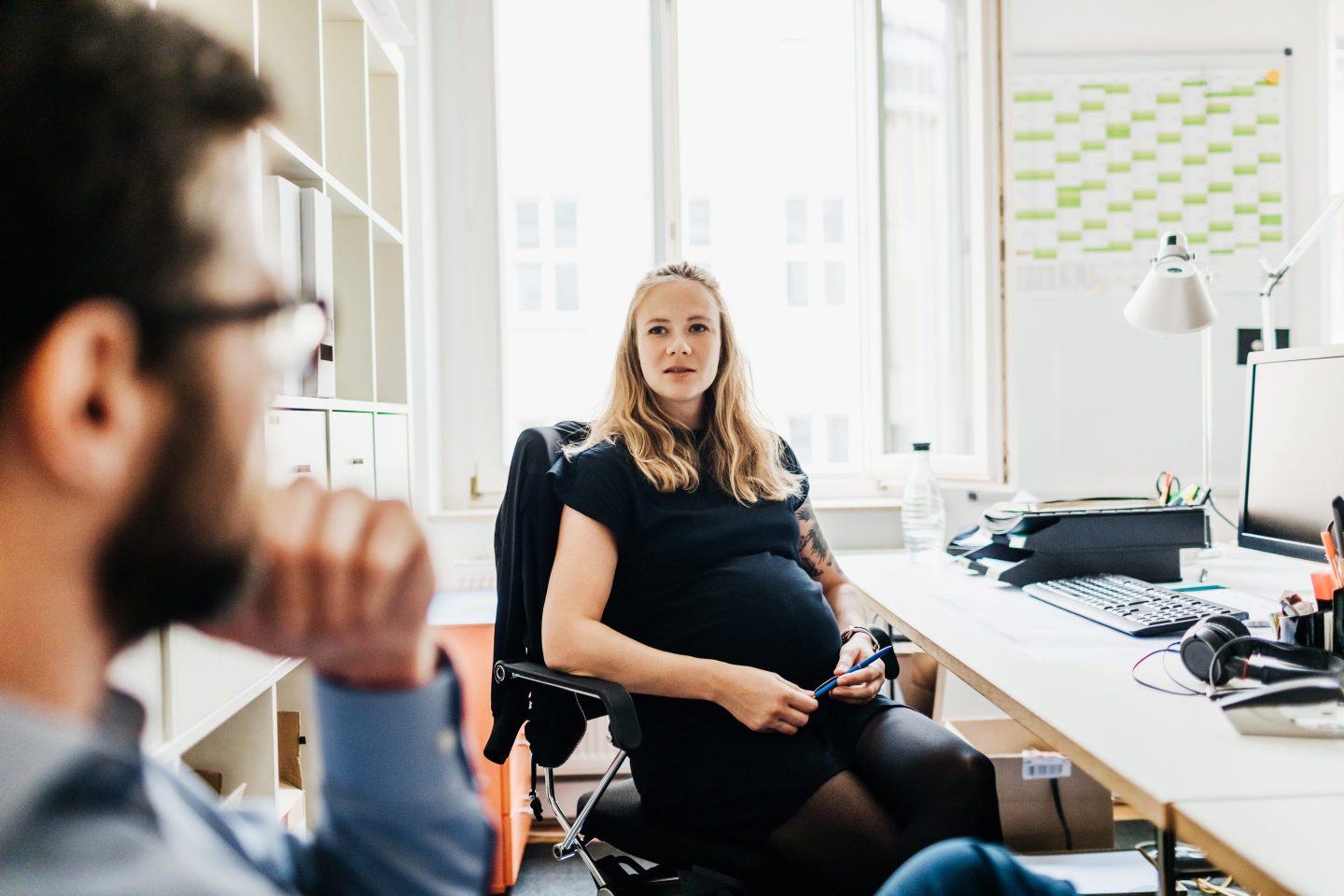 Pregnant Office Employee Talking To Colleague