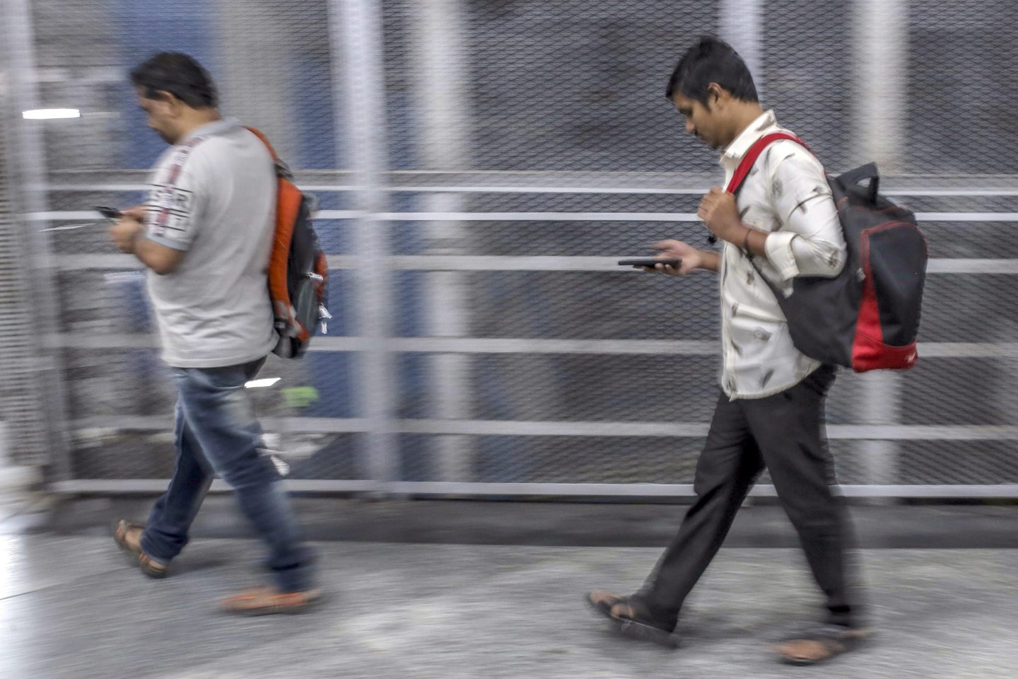 Pedestrians use smartphones while walking along a sidewalk in Mumbai, India.