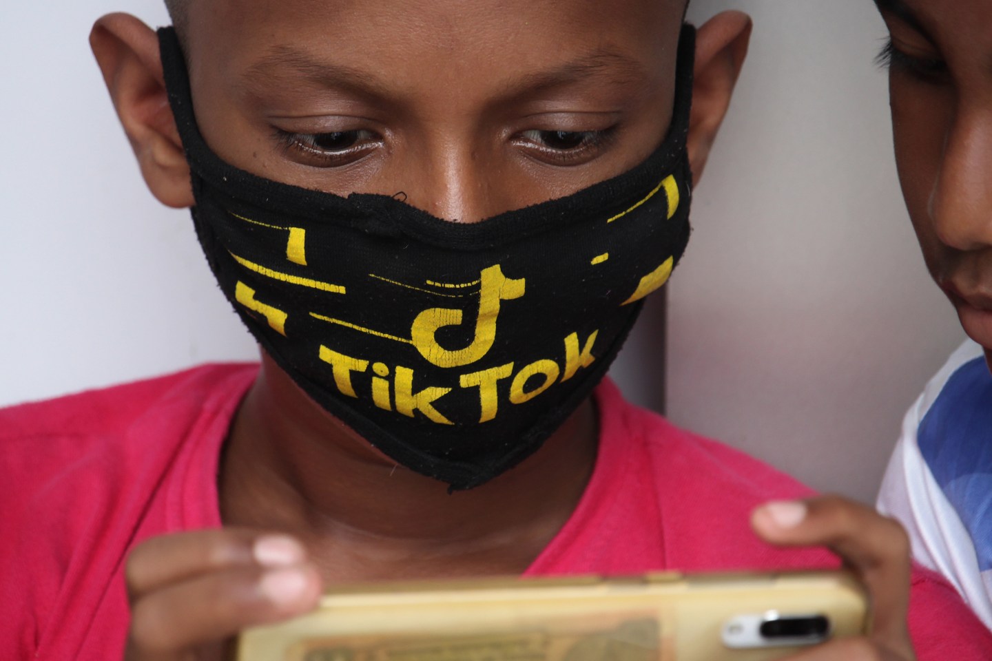 A boy wearing a face mask with the TikTok logo.