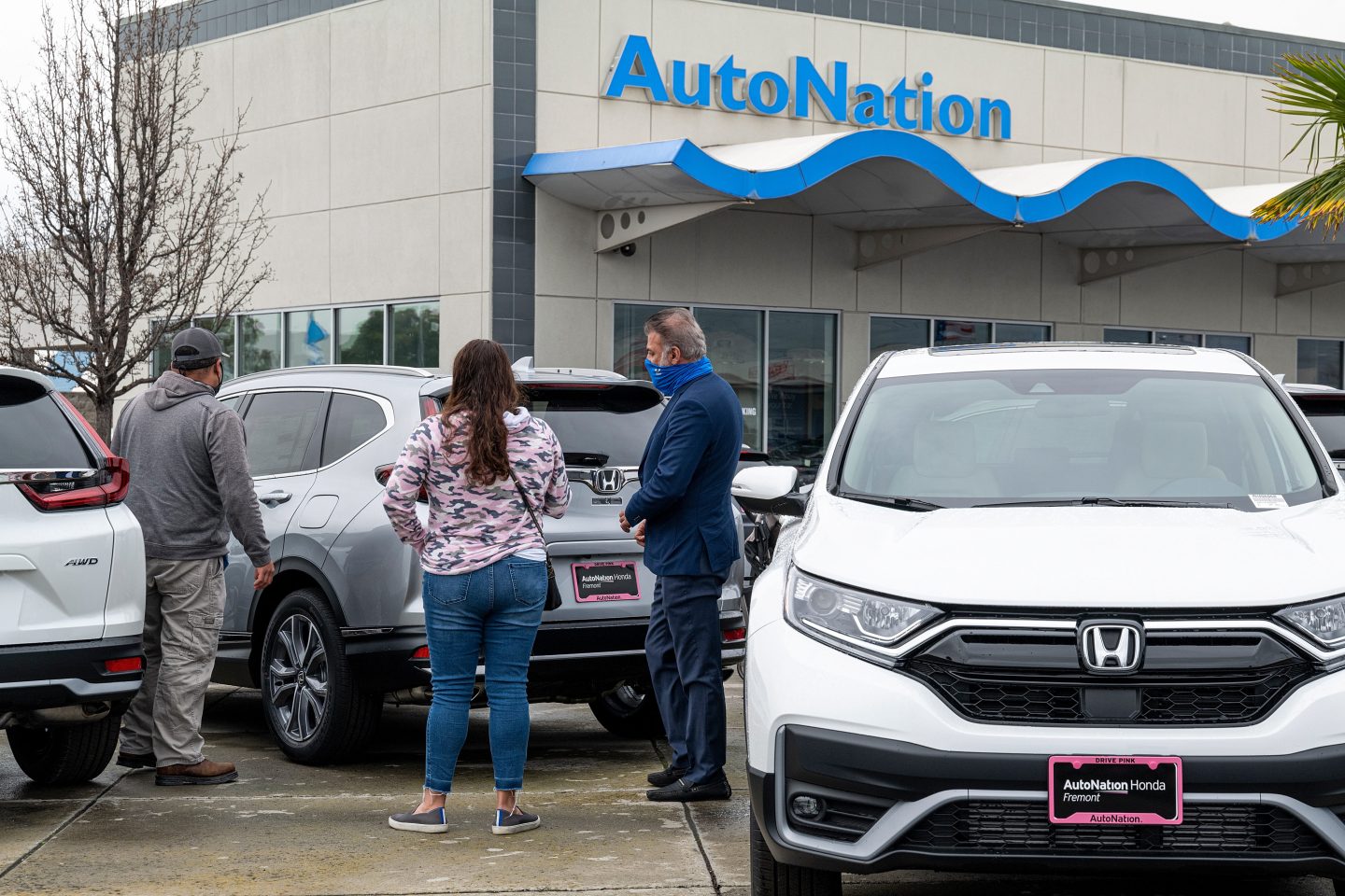 Customers look at a Honda vehicle with a salesperson at an AutoNation car dealership.