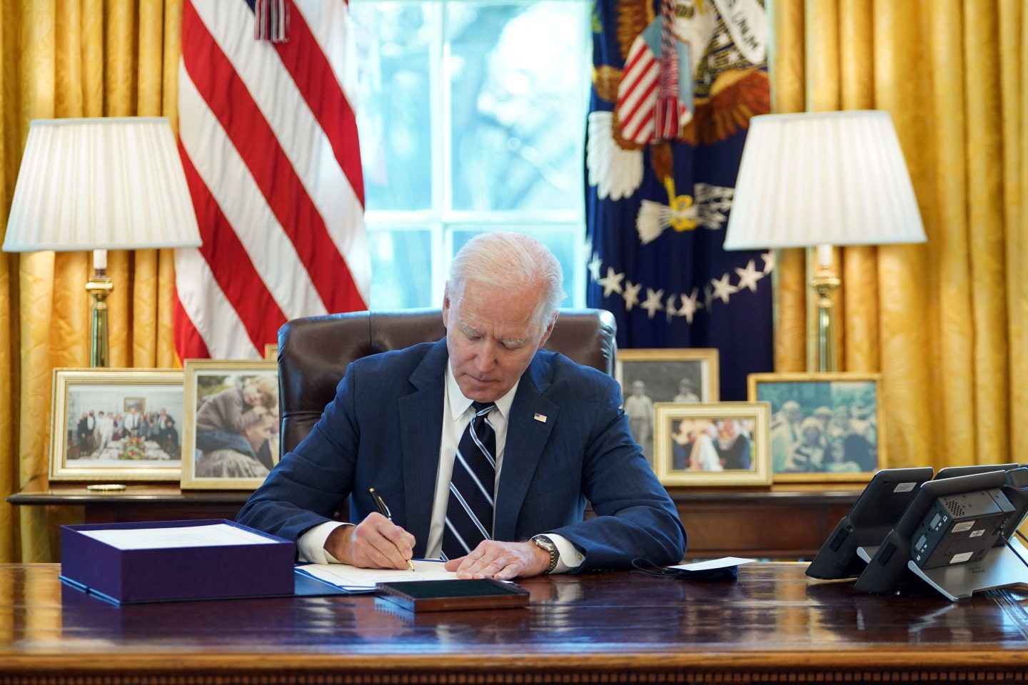 U.S. President Joe Biden signs the American Rescue Plan on March 11, 2021, in the Oval Office. The economic stimulus bill earmarked $350 billion for public services to counter the effects of the coronavirus pandemic.