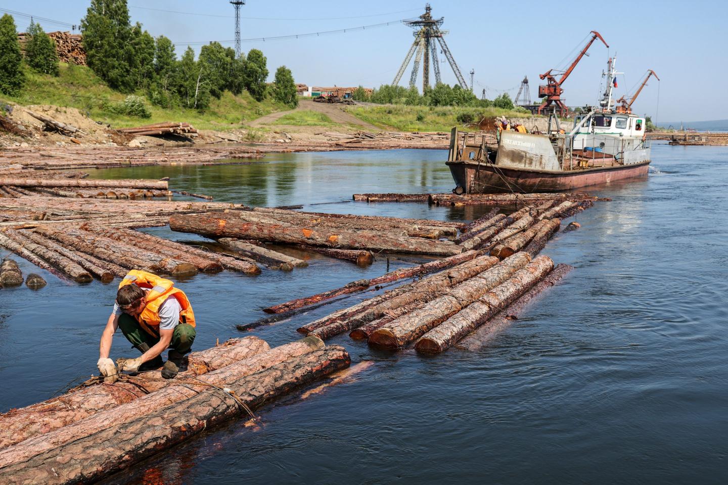 A Russian worker secures logs on a river