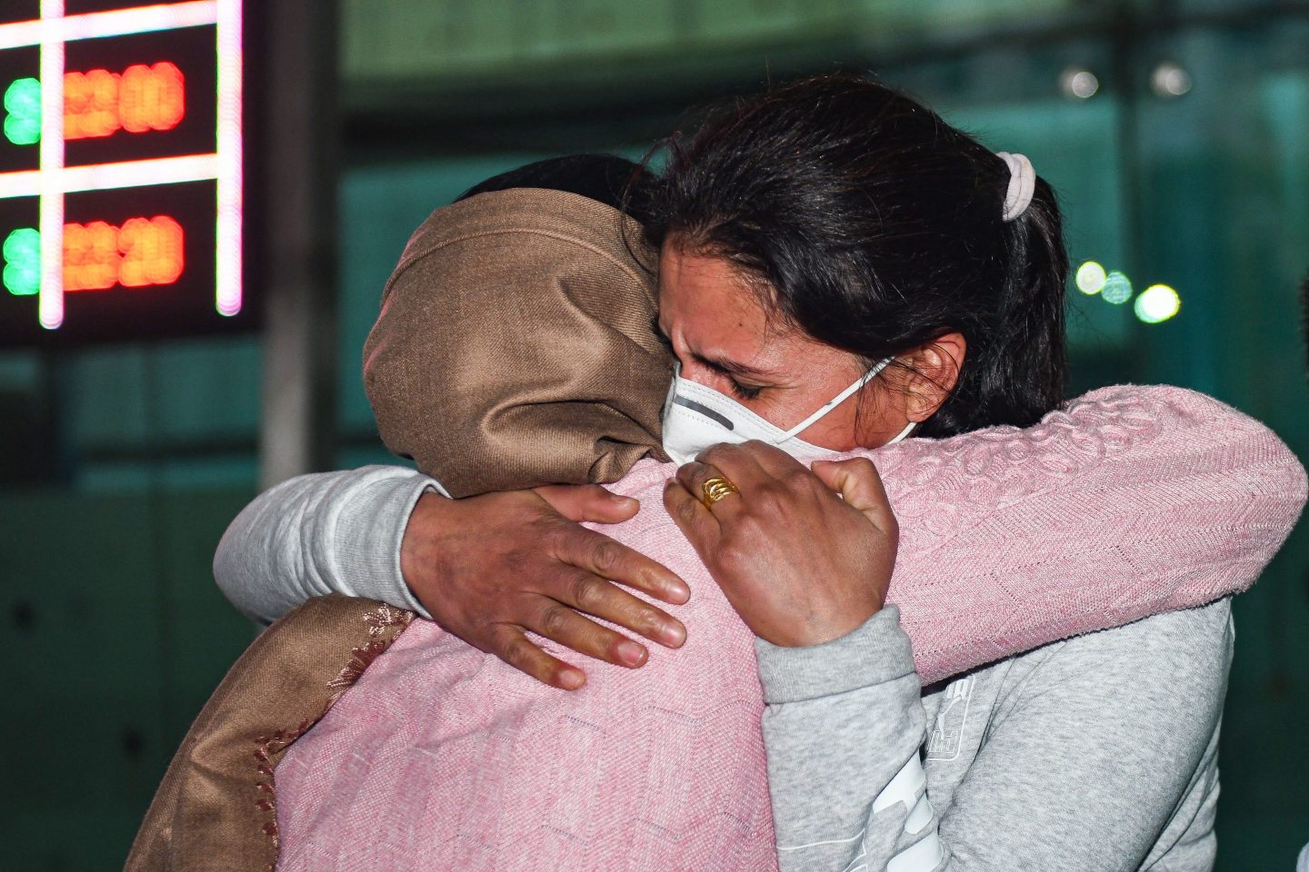 two women hug in an Indian airport.