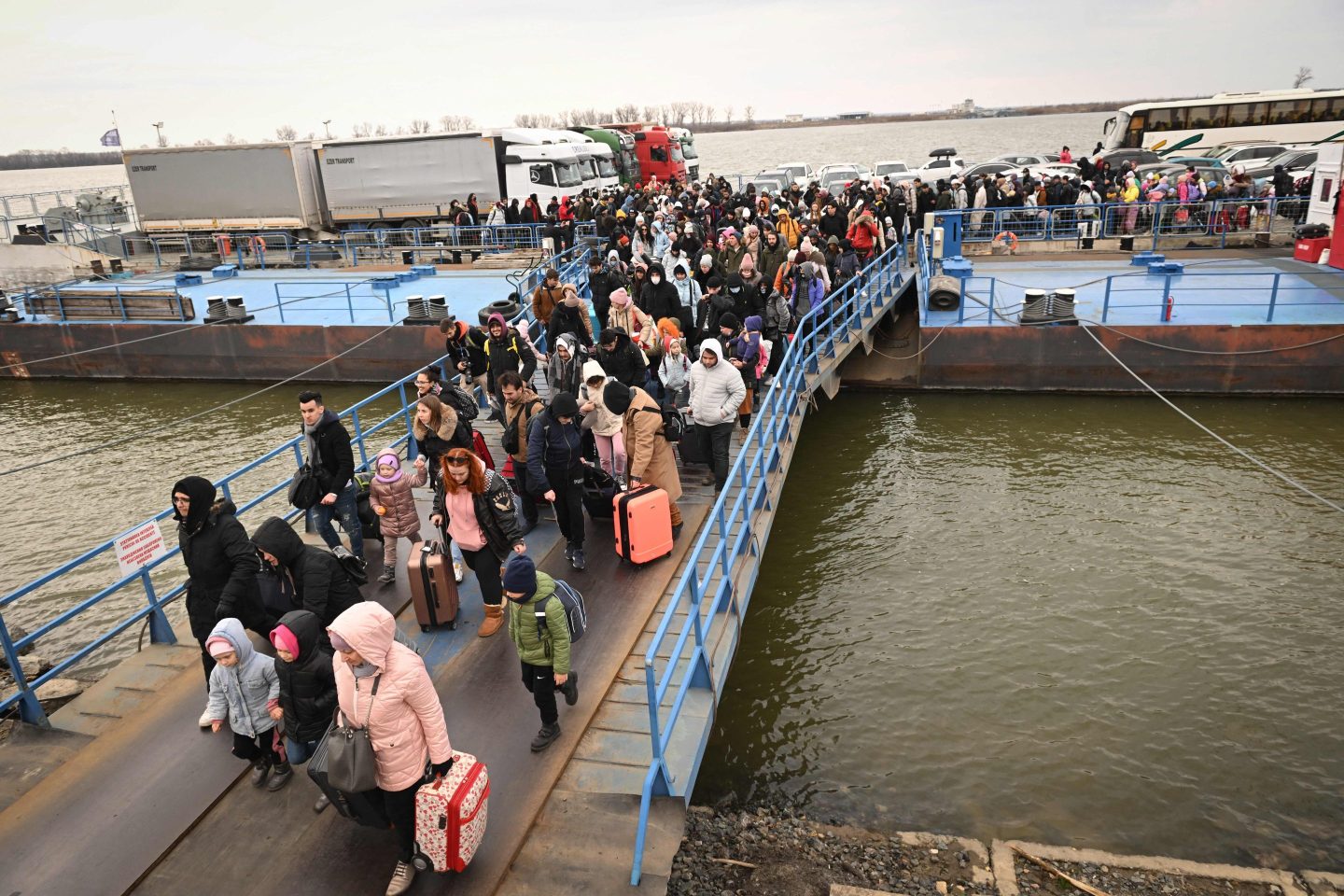 People coming from Ukraine descend from a ferry boat to enter Romania after crossing the Danube river at the Isaccea-Orlivka border crossing between Romania and Ukraine on February 26, 2022, as Ukrainians flee their country following Russia's invasion of Ukraine.