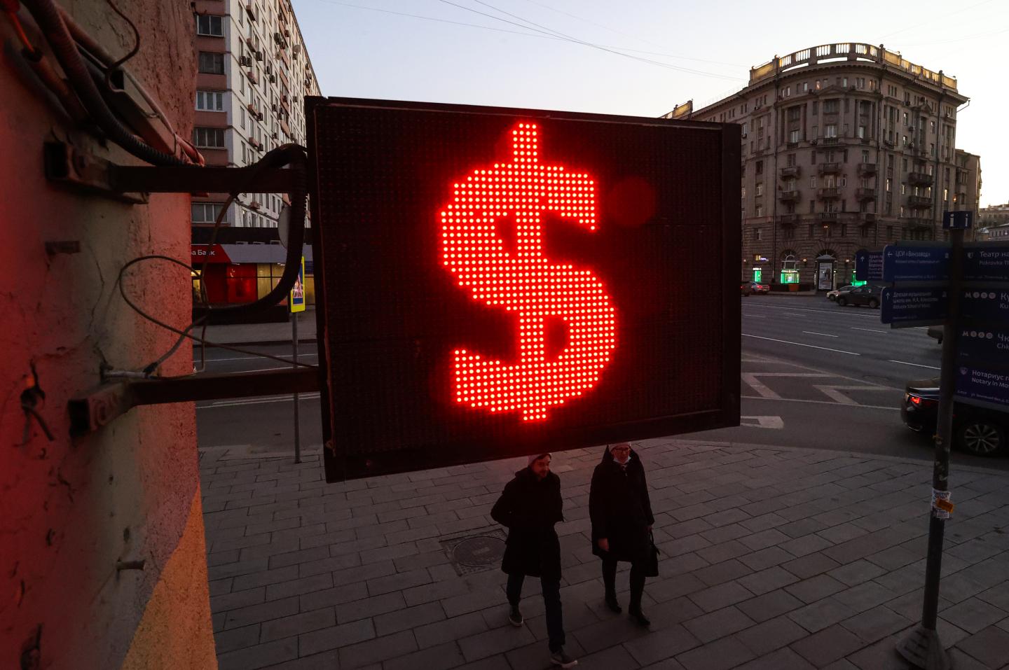 People walk by a U.S. dollar sign outside a currency exchange office in Moscow in this undated file photo.