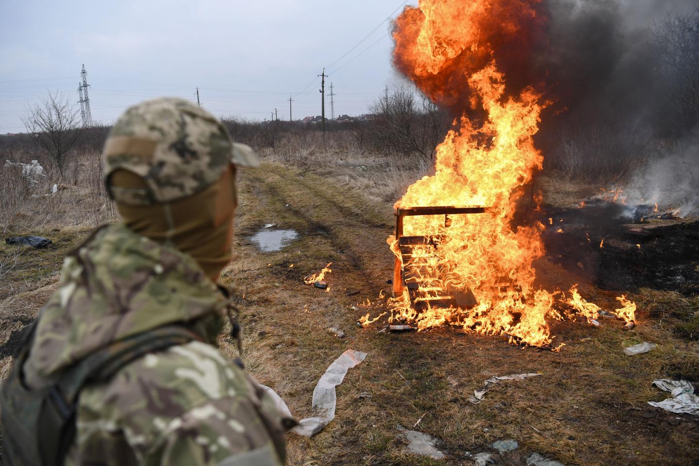 A Ukrainian soldier looks at flames in western Ukraine