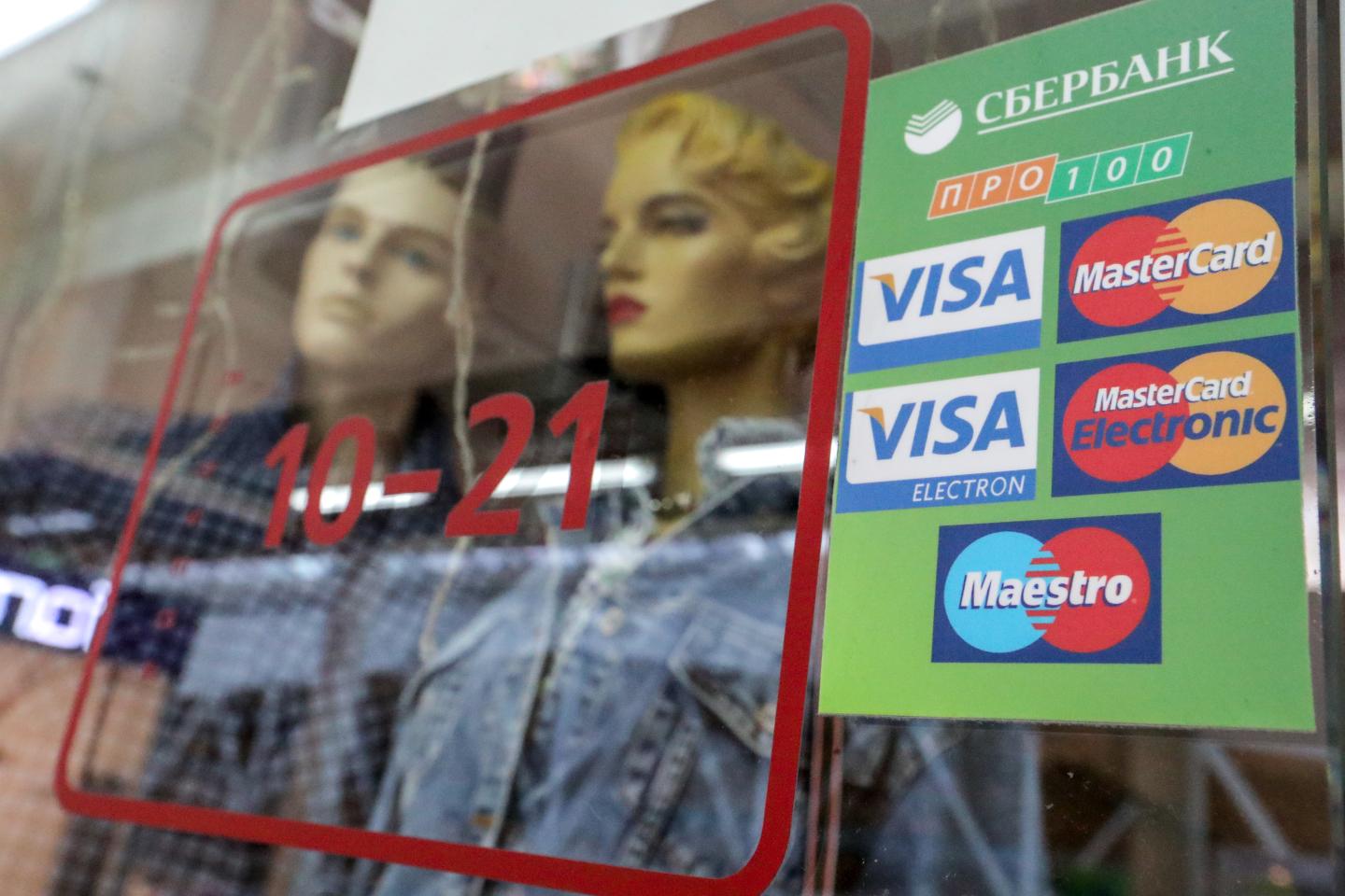 The logos of various payment systems with Sberbank written on them are pasted on a window of a store. Russia's largest bank - Sberbank - wants to ensure that people can pay and withdraw money with their cards even after Visa and Mastercard credit cards are switched off.