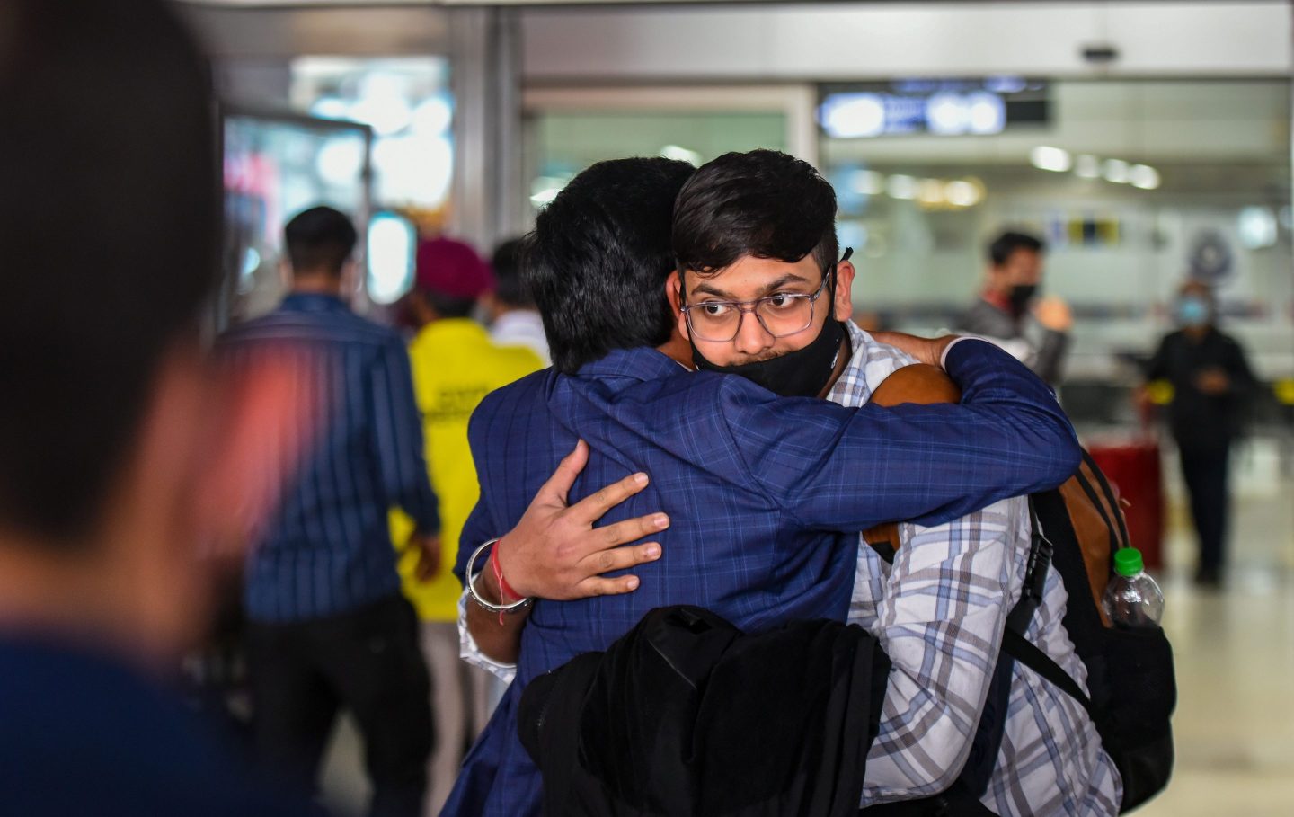 Two men hug at Indian airport.