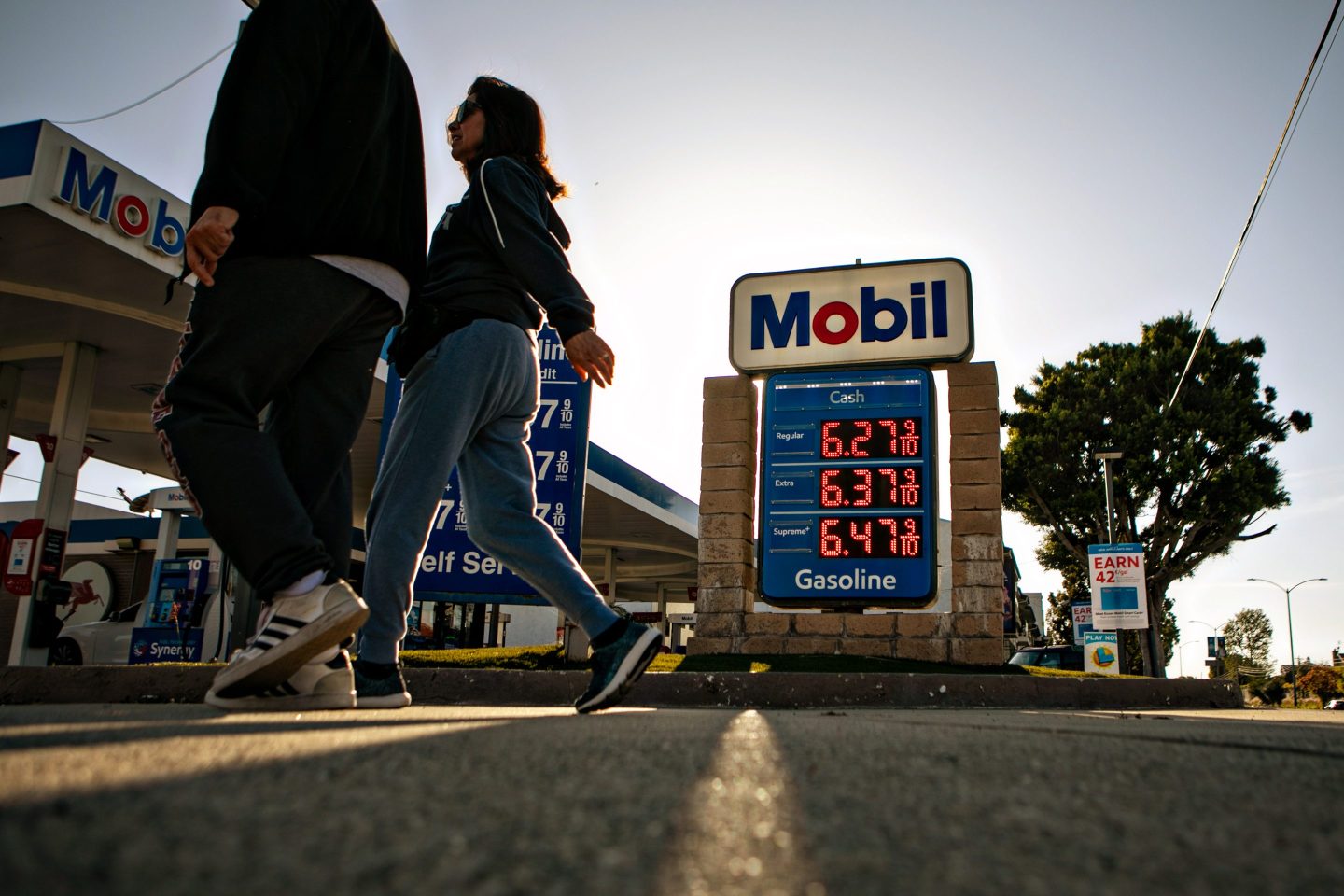 People walking in front of a gas station sign.