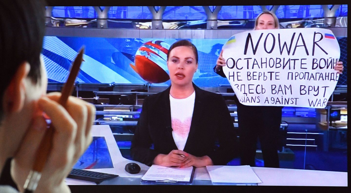 A woman looks at a computer screen watching a dissenting Russian Channel One employee entering Ostankino on-air TV studio during Russia's most-watched evening news broadcast, holding up a poster which reads as "No War" and condemning Moscow's military action in Ukraine in Moscow on March 15, 2022.