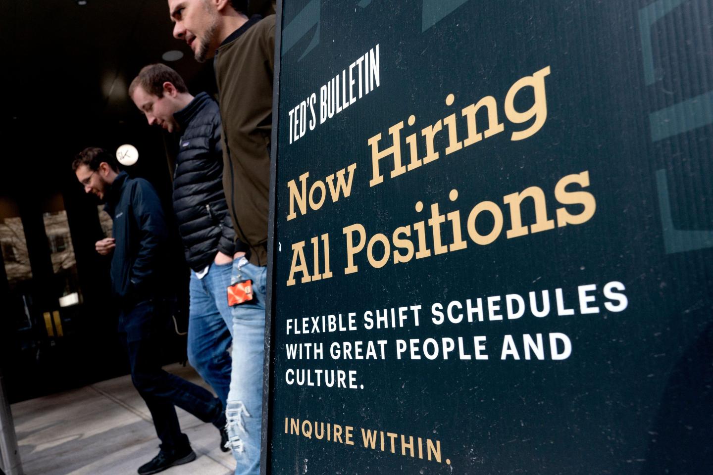 People walking past now hiring sign