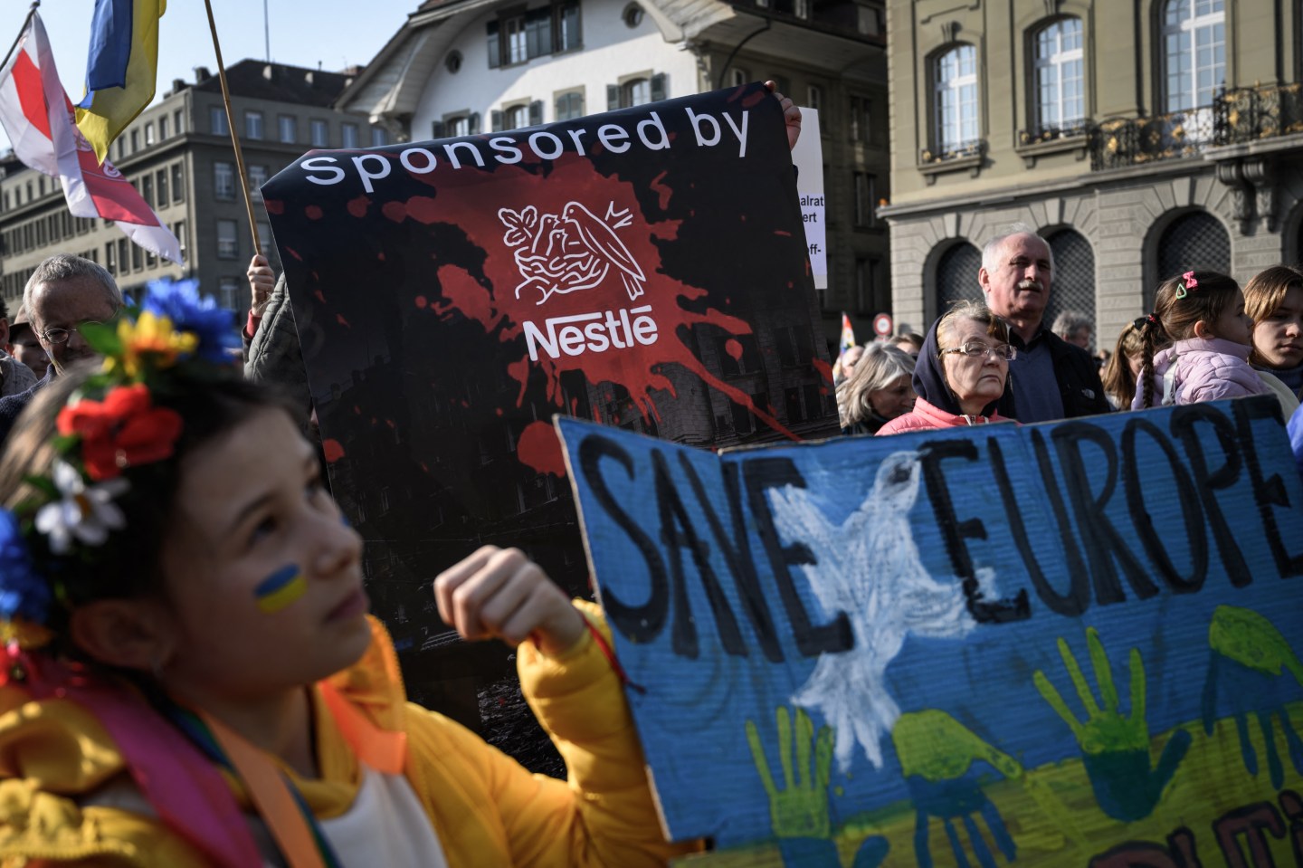 Protesters hold a banner against Swiss food giant Nestle during a demonstration against the Russian invasion of Ukraine next to the Swiss House of Parliament in Bern, on March 19, 2022.