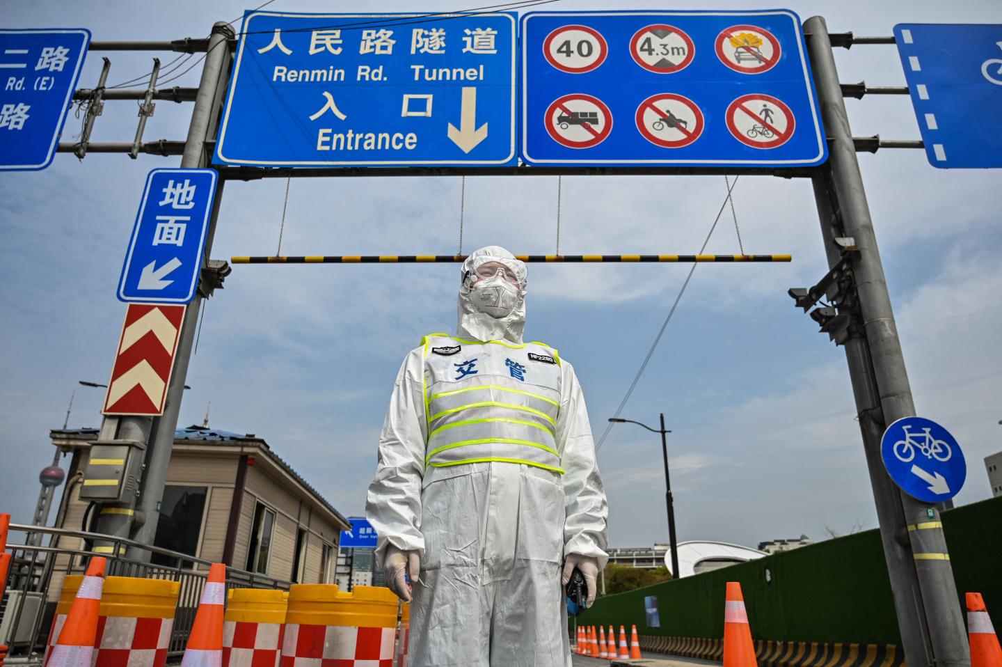 A worker in a hazmat suit guards a tunnel connecting East and West Shanghai