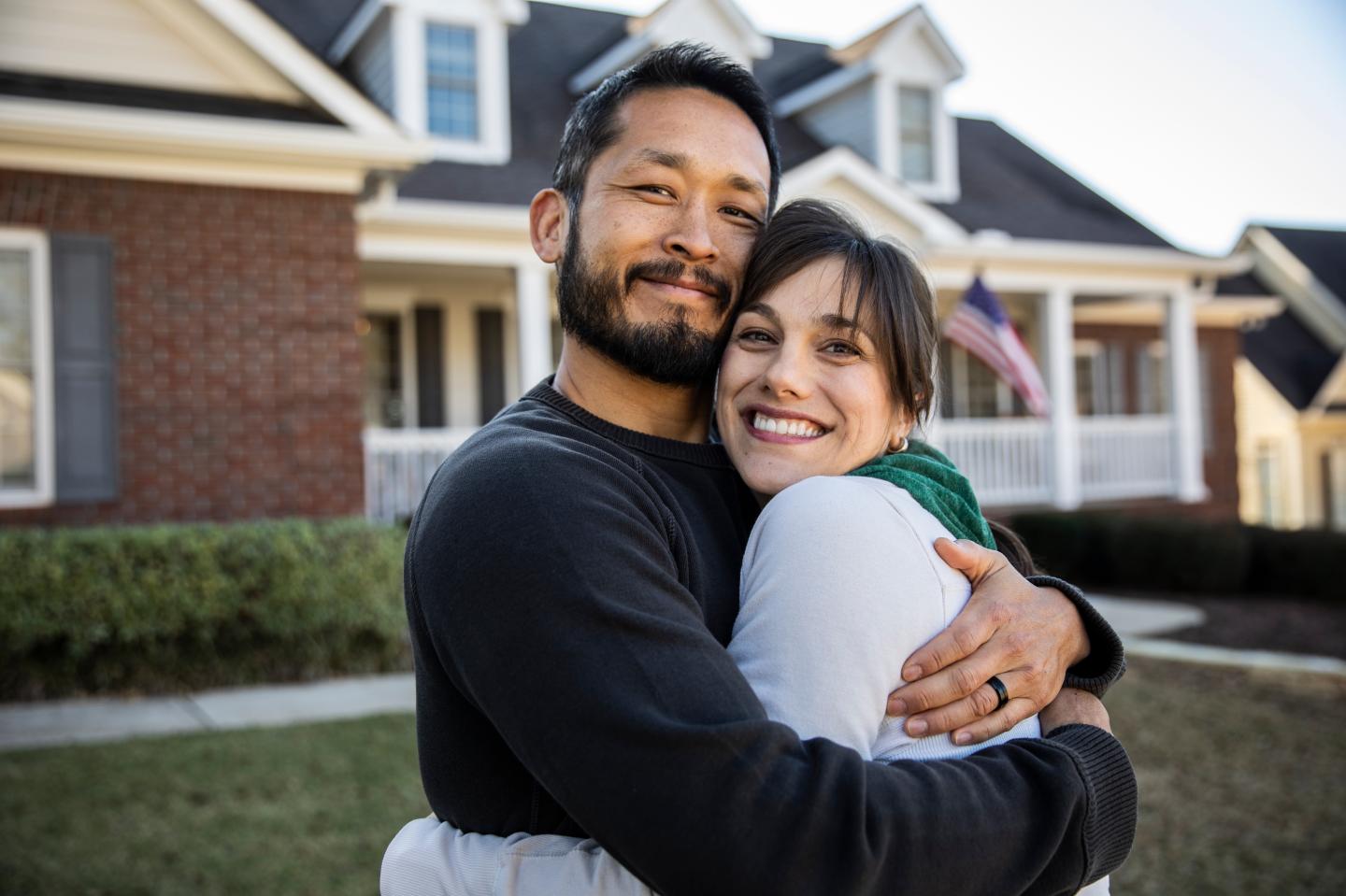 A man and a woman in front of a home.