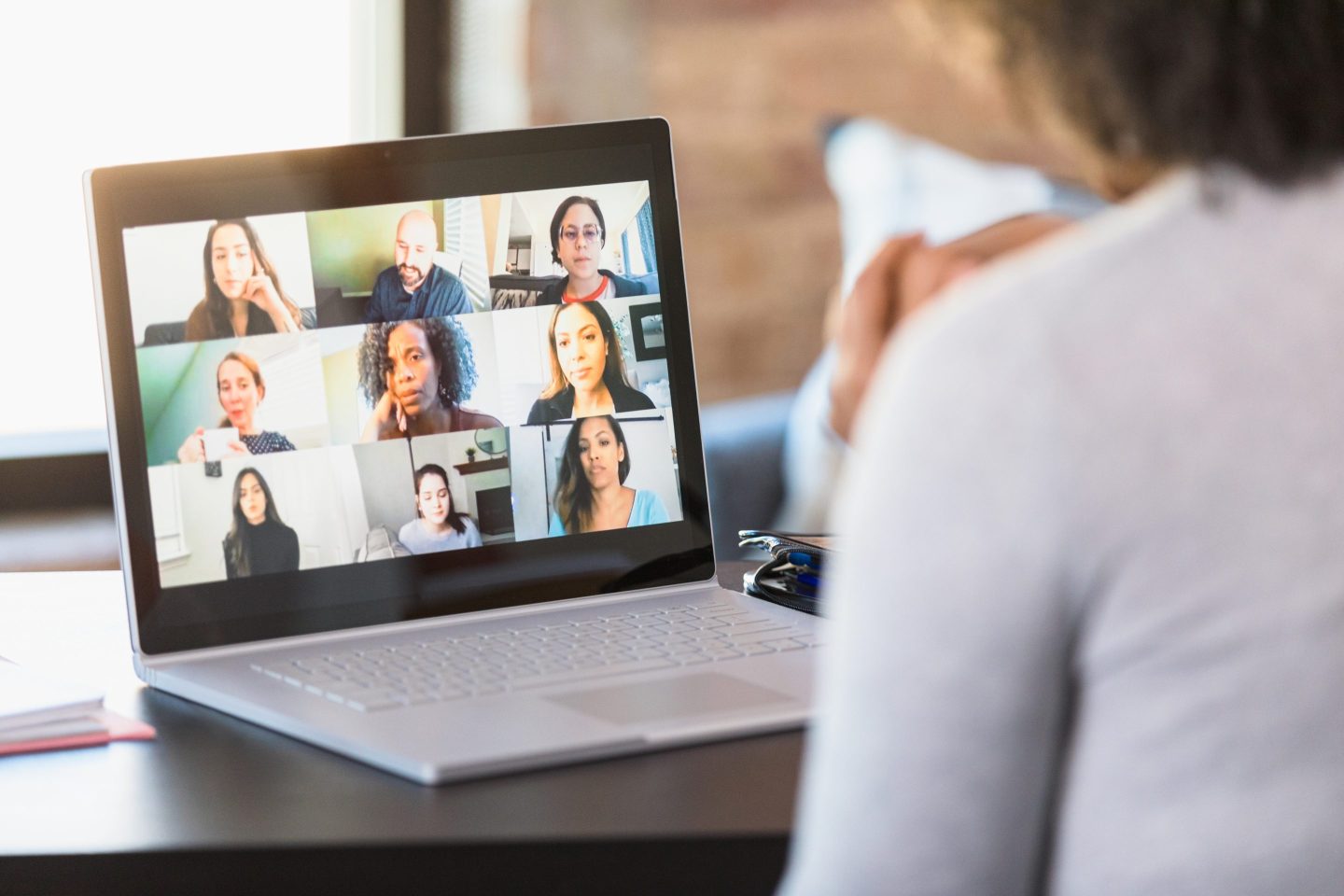 A woman uses her laptop to videoconference with her colleagues