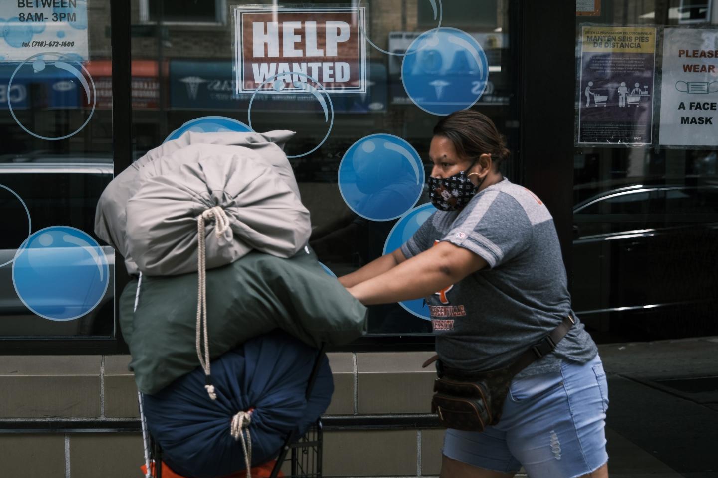 Woman walks by help wanted sign
