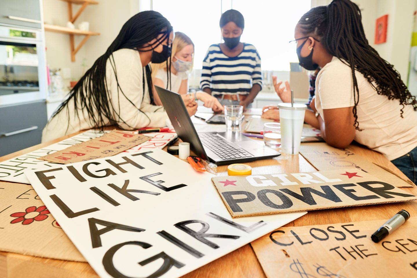Teenagers in face masks making signs for a women's rights march