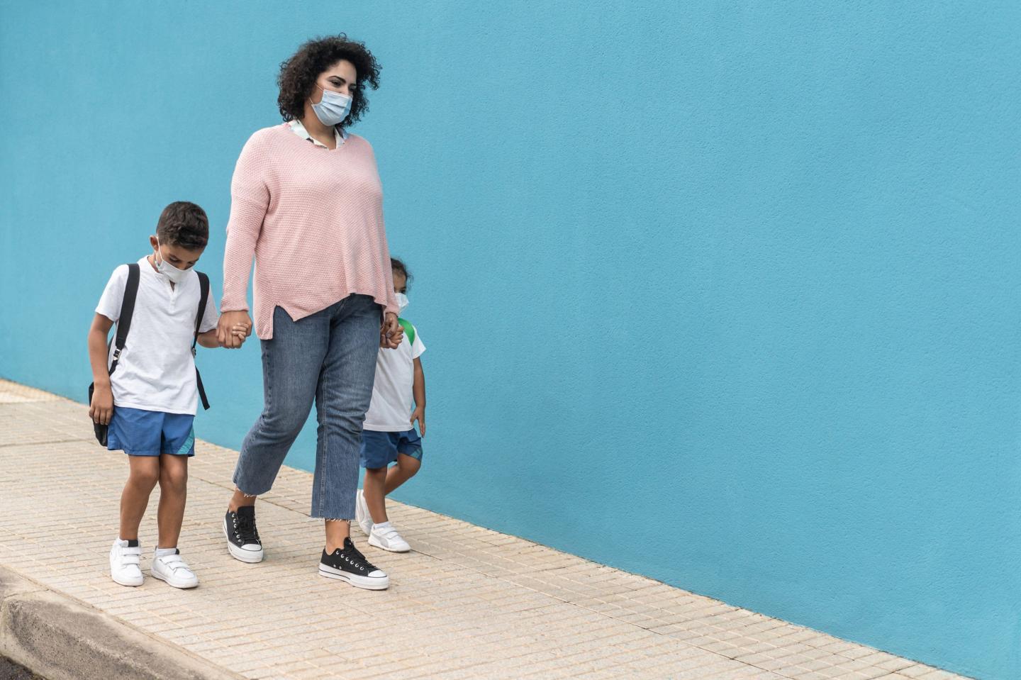 Mother walks her children to school.