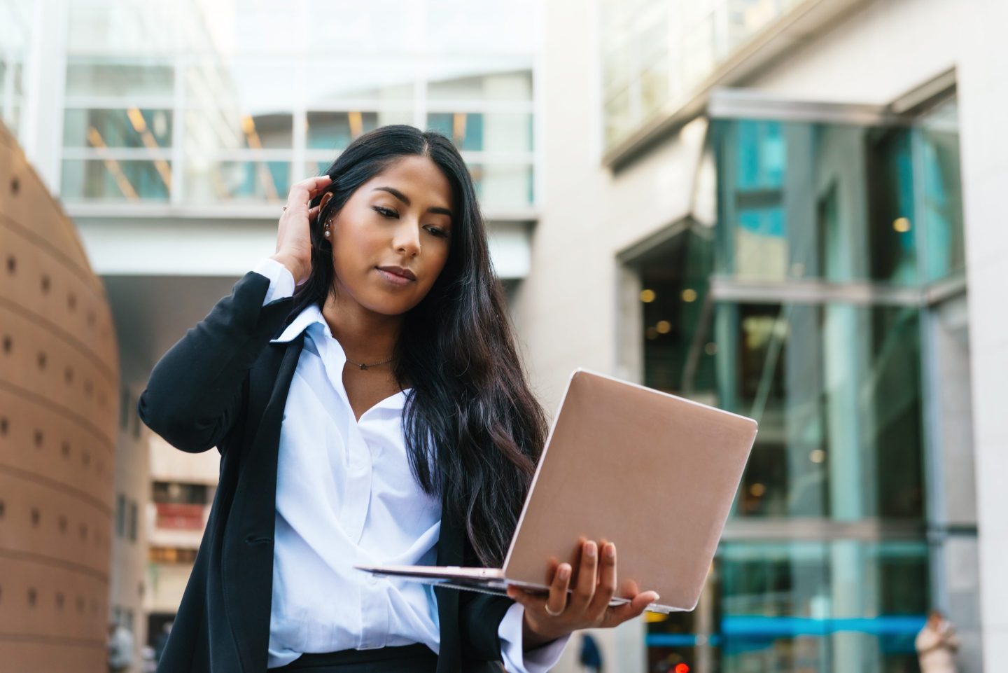 Businesswoman holding laptop outside a building.