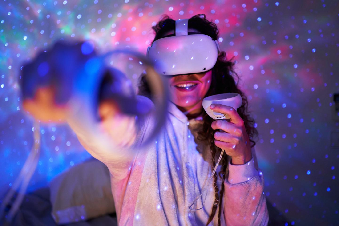 A cheerful young woman experiments with a virtual reality headset in a dark room