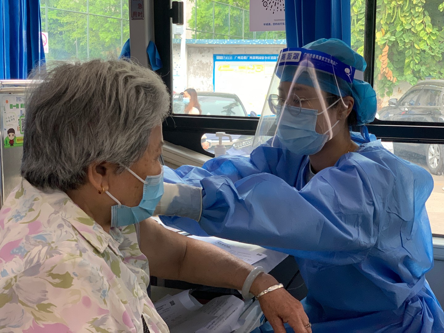 A health worker vaccinated an elderly woman on board a mobile vaccine bus in Guangzhou, China