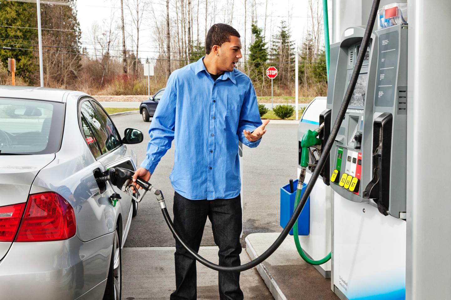 A stock photo of a young man filling up his gas tank.