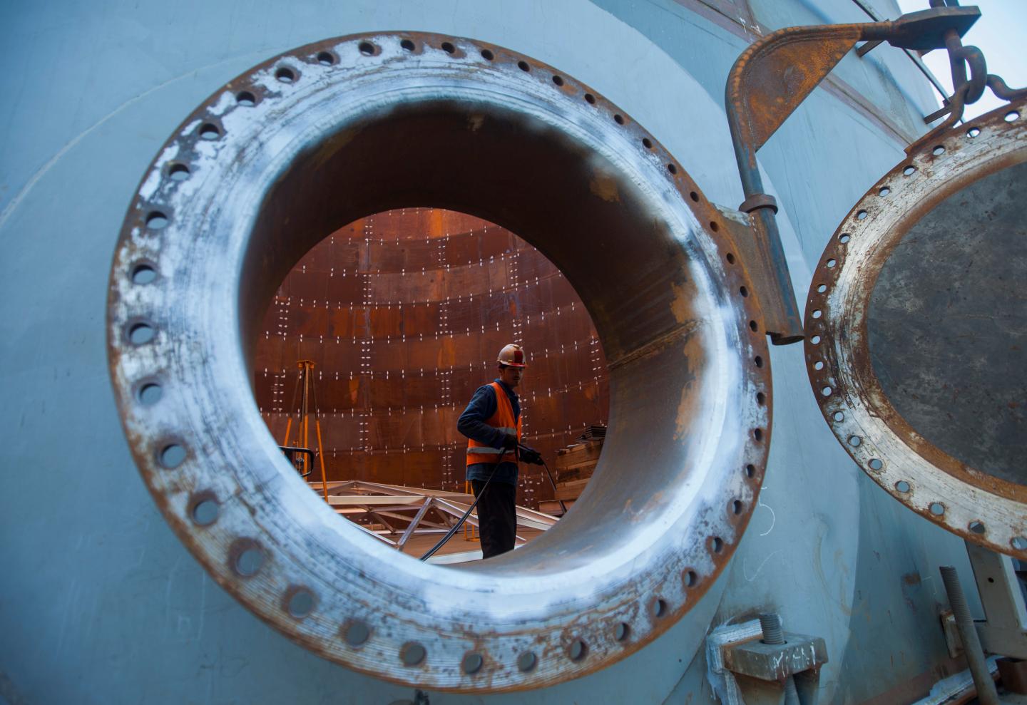 A construction worker is seen through the porthole of an under construction fuel storage tank at the VTTV oil storage terminal, a joint venture of Vitol Group and MISC Bhd., in Vasilikos, Cyprus, on Friday, Feb. 21, 2014.