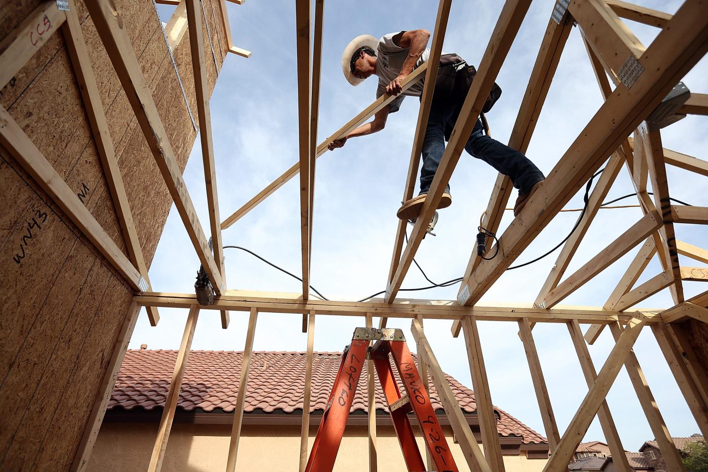 A worker walks across beams while building a new home in Phoenix, Arizona.