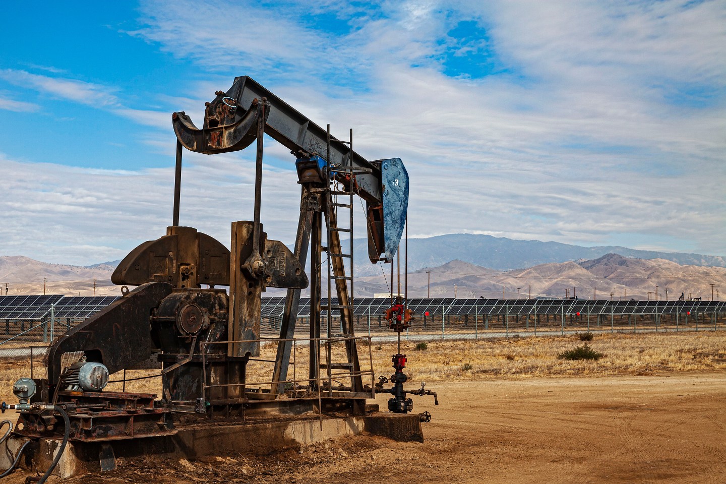 A pumpjack rigging oil next to solar panels in Kern County, California.