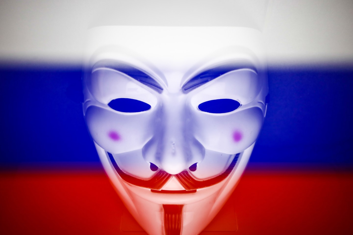 Russian flag displayed on a laptop screen and Guy Fawkes mask are seen in this multiple exposure illustration photo.